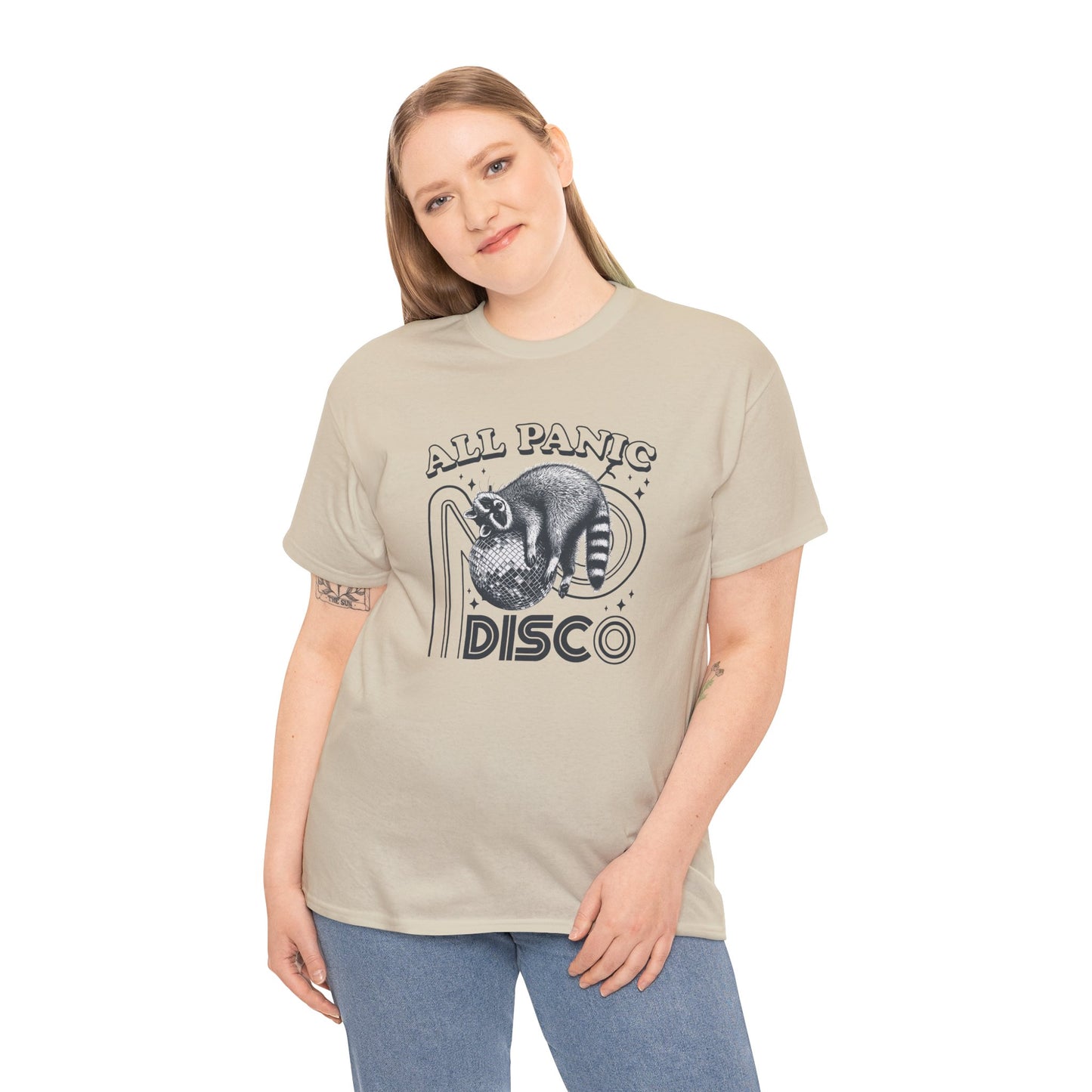 Model wearing a beige T-shirt featuring "All Panic No Disco" text with a raccoon illustration inside a disco ball. Part of the Vivid Divergence Sensory Friendly Unisex Tees Range.