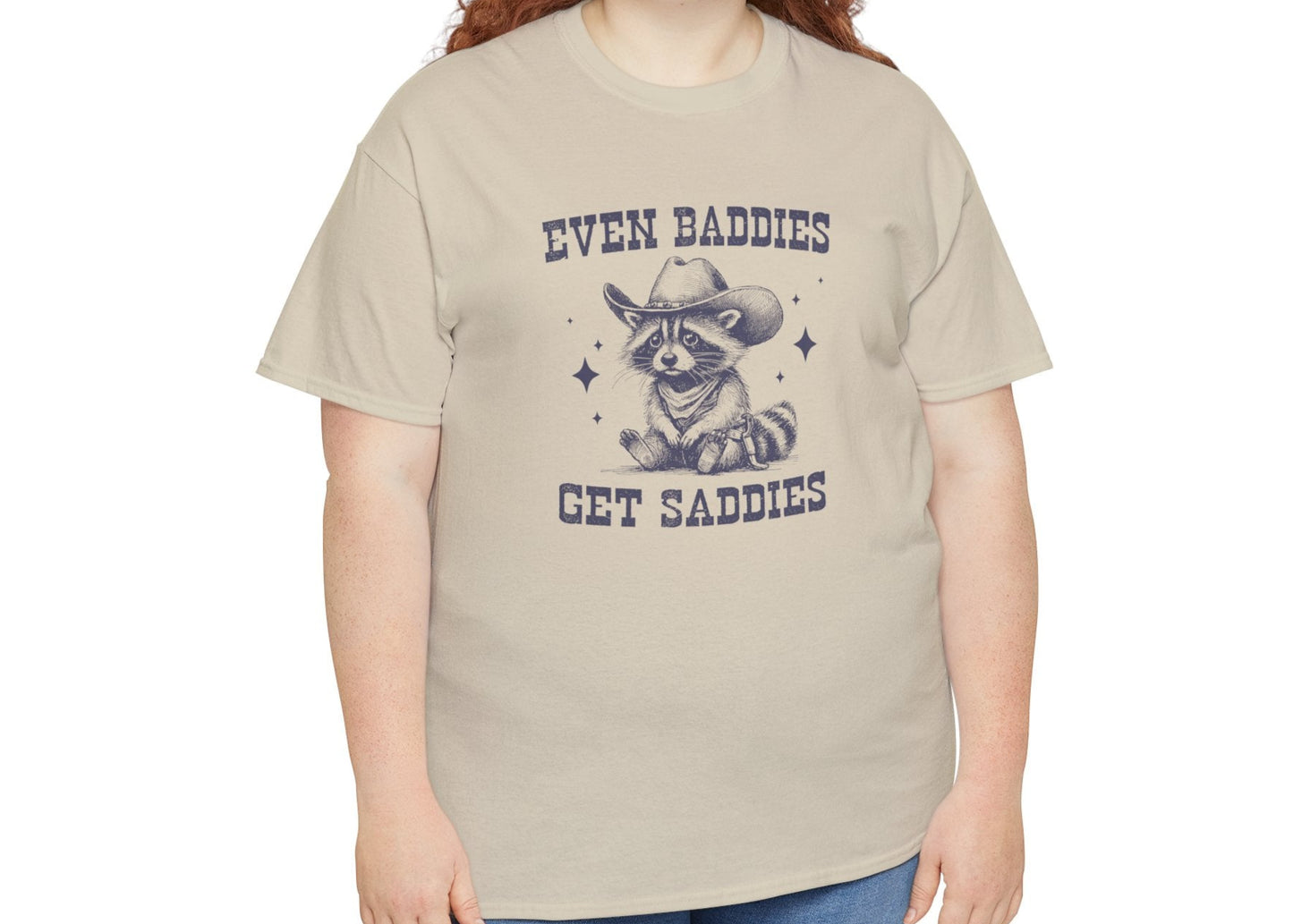 Model wearing a beige T-shirt featuring the text "Even Baddies Get Saddies" and a crying eye graphic. Part of the Vivid Divergence Sensory Friendly Unisex Tees Range.