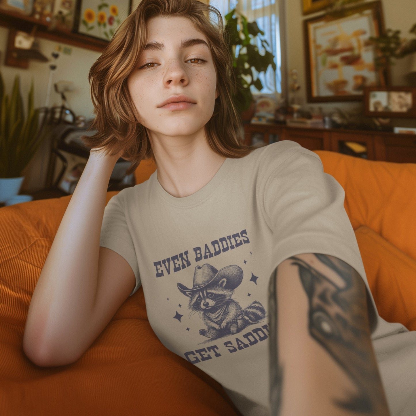 Model wearing a beige T-shirt featuring the text "Even Baddies Get Saddies" and a crying eye graphic. Part of the Vivid Divergence Sensory Friendly Unisex Tees Range.