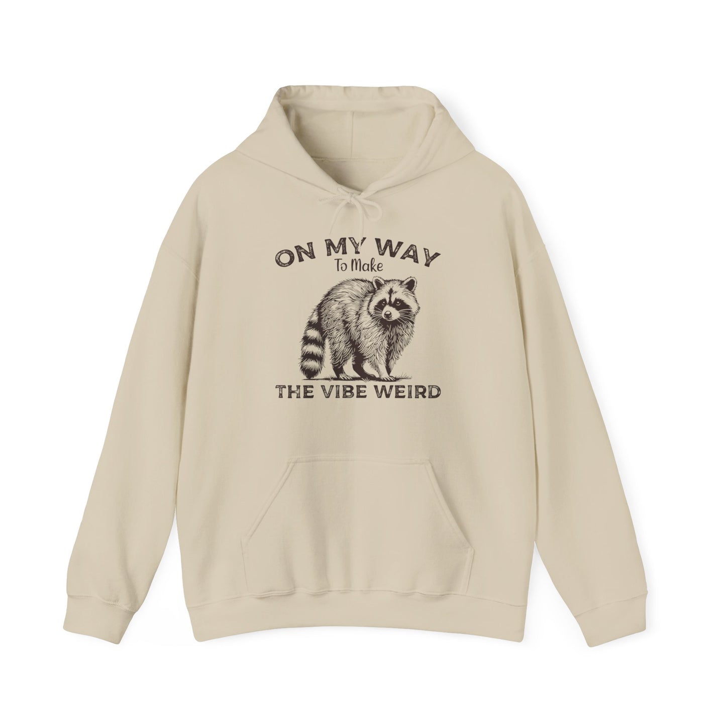Front view of a beige hoodie featuring the text "On My Way to Make the Vibe Weird" and a cartoon illustration of a raccoon holding a stick. Part of the Vivid Divergence Sensory Friendly Unisex Hoodie Range.
