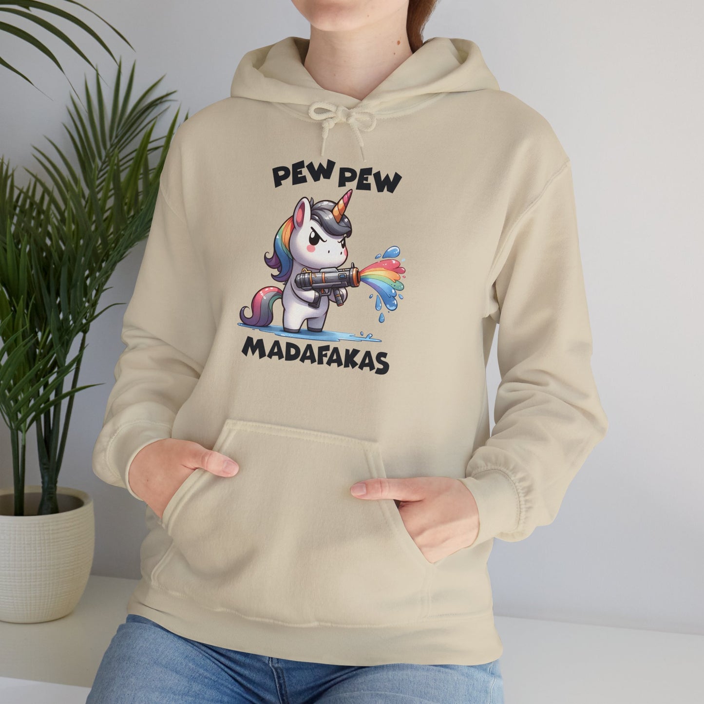 Model wearing a beige hoodie featuring the text "Pew Pew Madafakas" and a cartoon illustration of a unicorn holding a rainbow water gun. Part of the Vivid Divergence Sensory Friendly Unisex Hoodie Range.