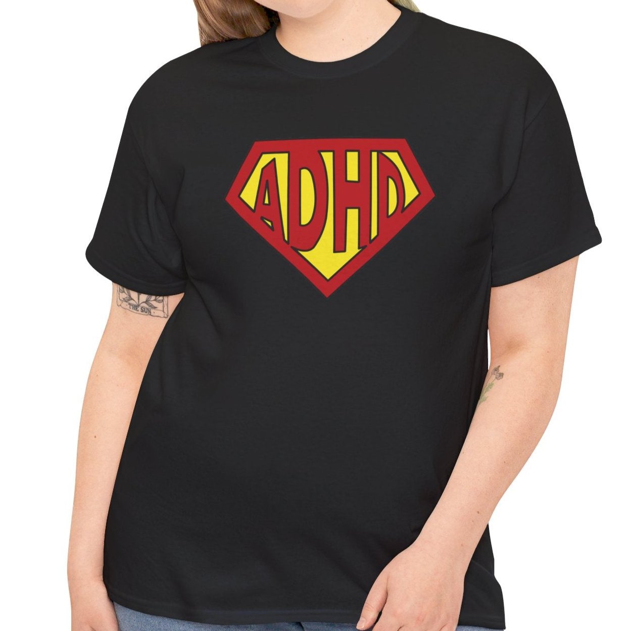 Modeled view of a black T-shirt featuring a yellow and red ADHD logo styled in the Superman symbol. Part of the Vivid Divergence Sensory Friendly Unisex Tees Range.