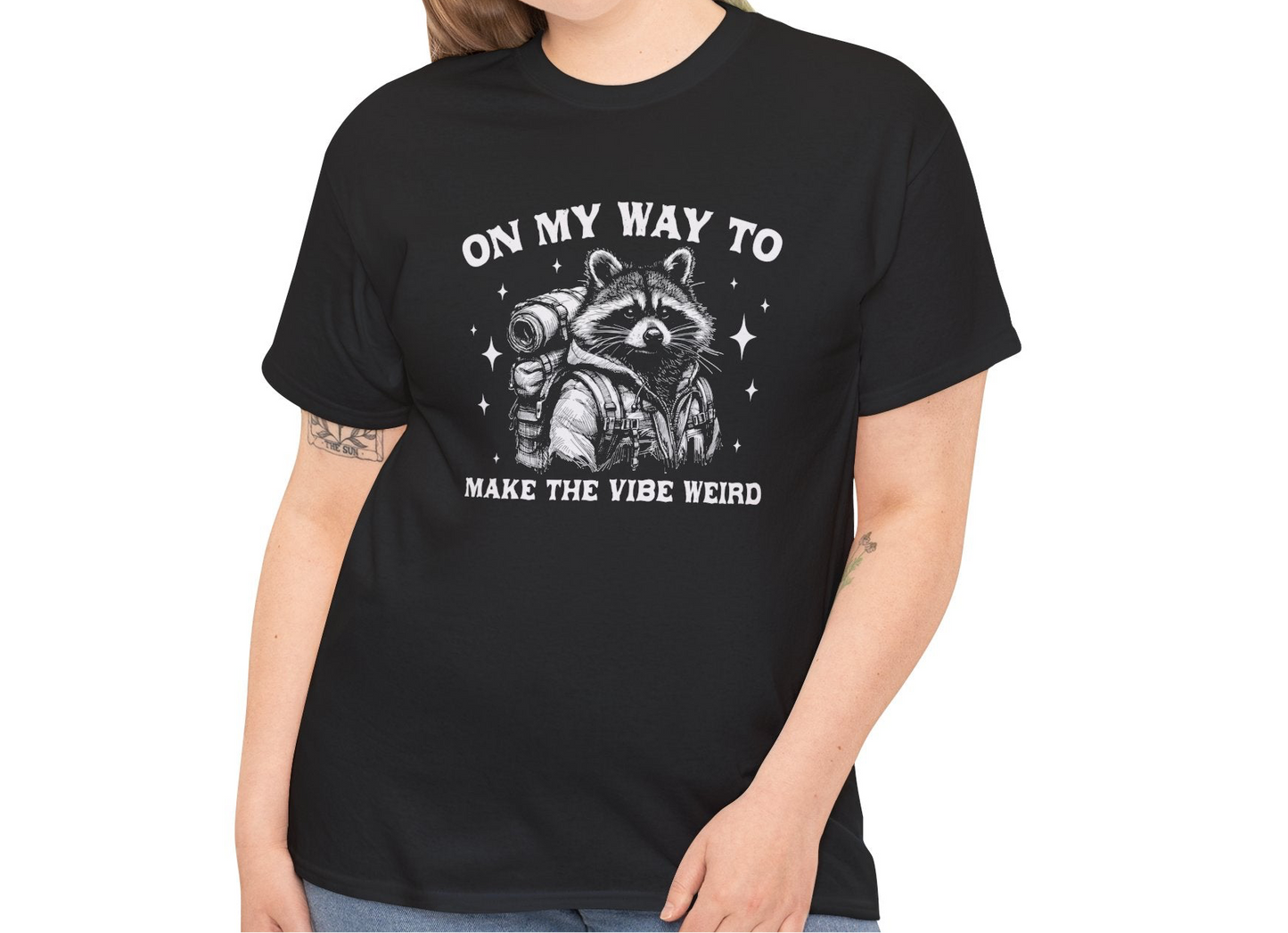 Model wearing a black T-shirt with "On My Way to Make the Vibe Weird" and a raccoon graphic in white text. Part of the Vivid Divergence Sensory Friendly Unisex Tees Range.