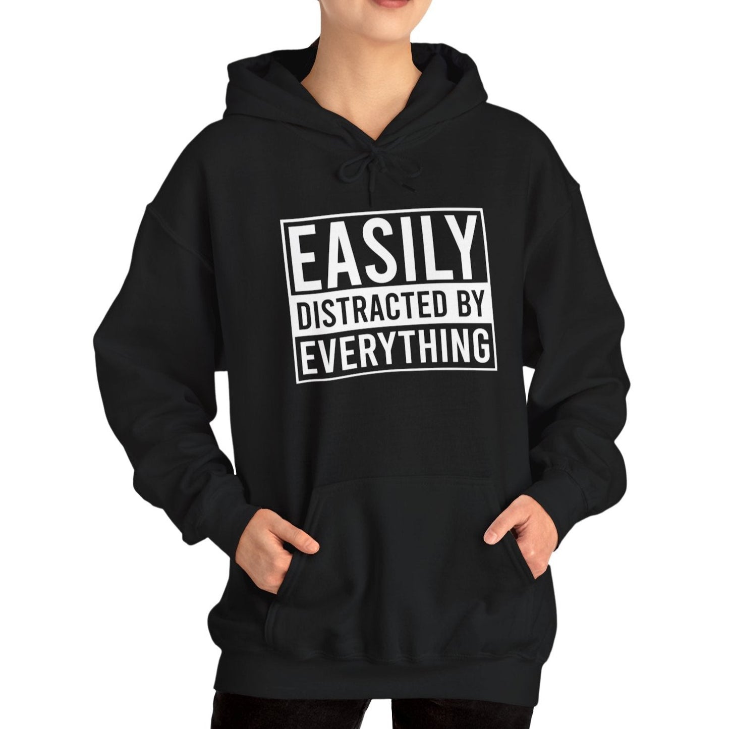 Model wearing a black hoodie with the text "Easily Distracted by Everything" in bold white lettering. Part of the Vivid Divergence Sensory Friendly Unisex Hoodie Range.
