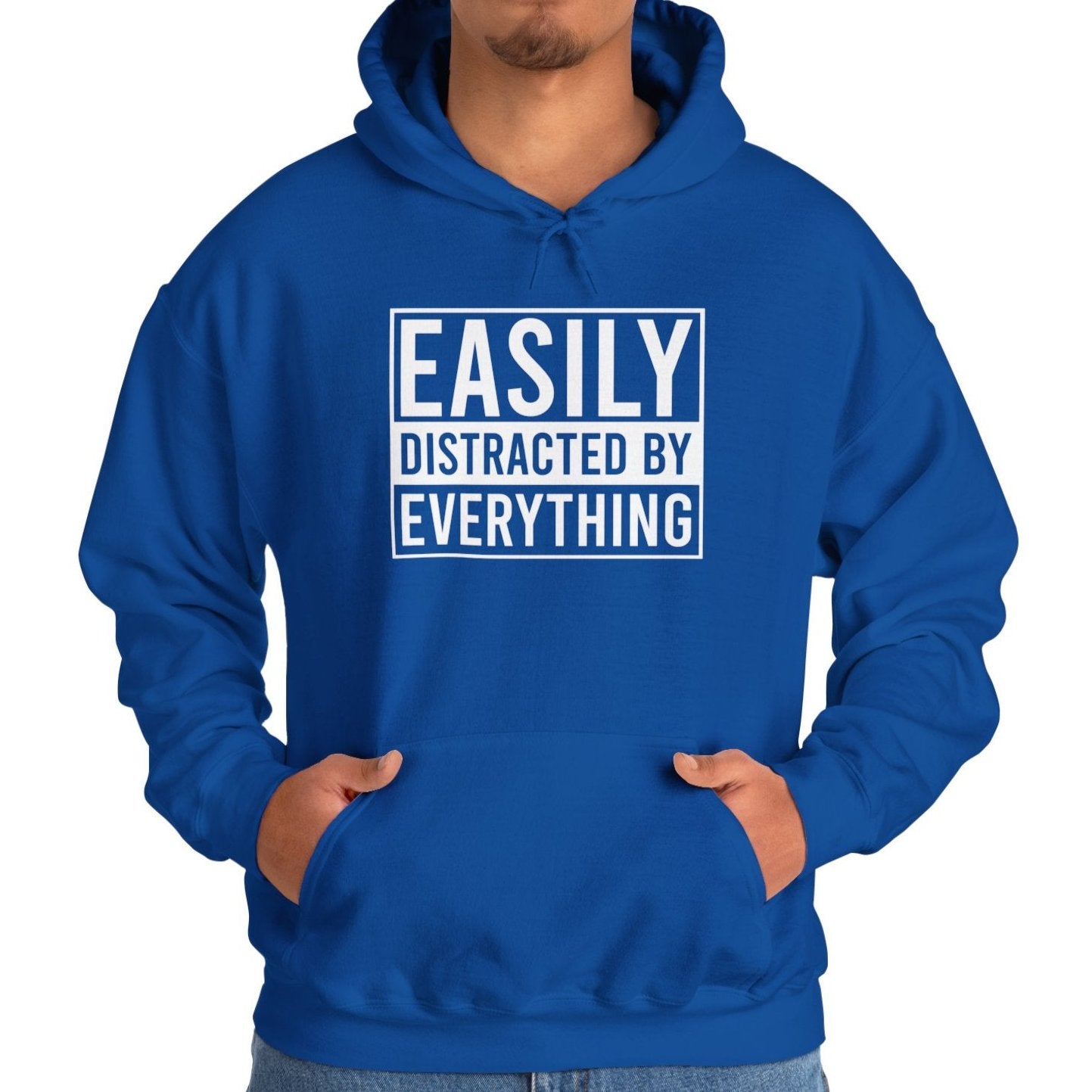 Model wearing a blue hoodie with the text "Easily Distracted by Everything" in bold white lettering. Part of the Vivid Divergence Sensory Friendly Unisex Hoodie Range.