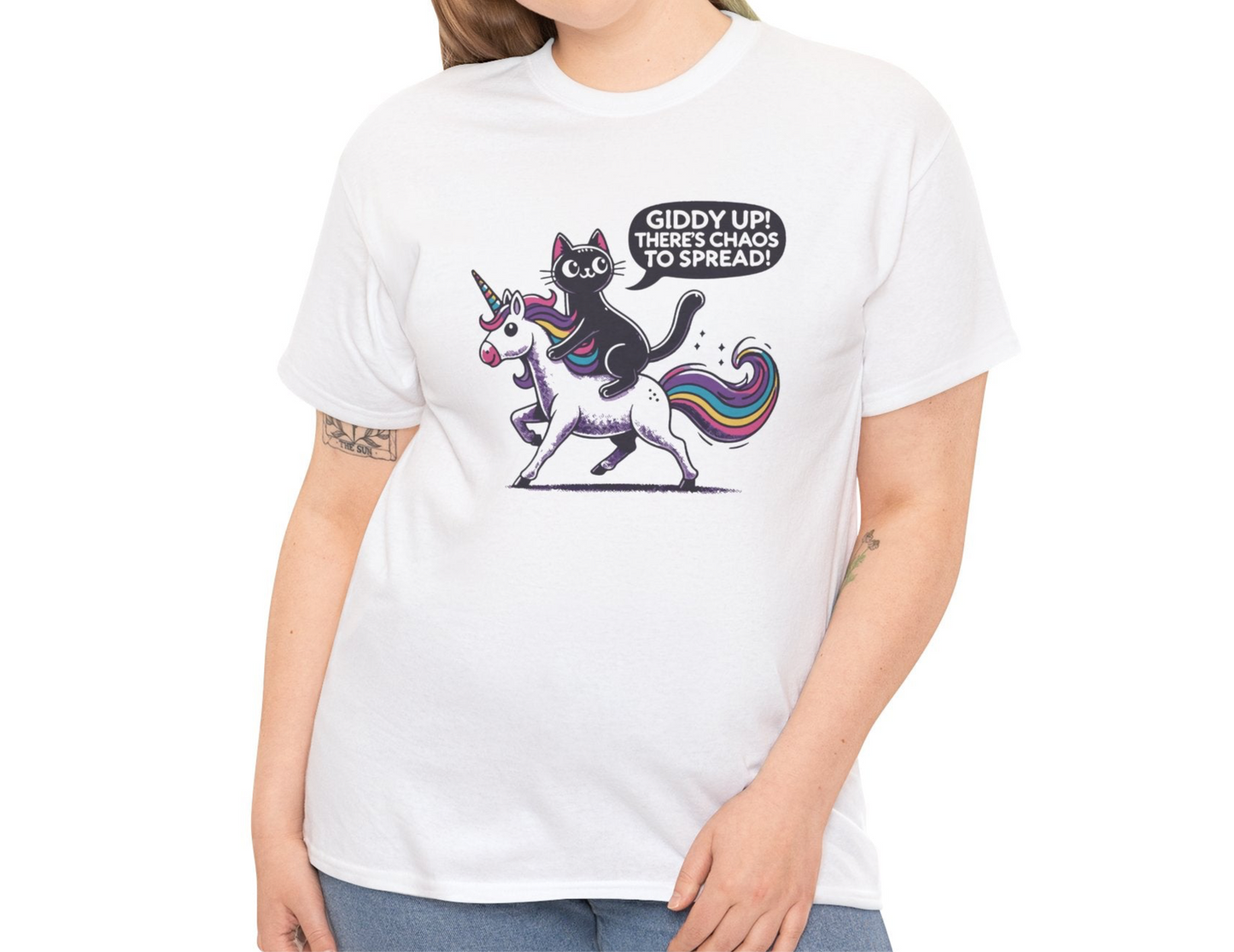 Close-up of a person wearing a white T-shirt with a design of a black cat riding a unicorn and the text "Giddy Up, There's Chaos to Spread." Part of the Vivid Divergence Sensory Friendly Unisex Tees Range.