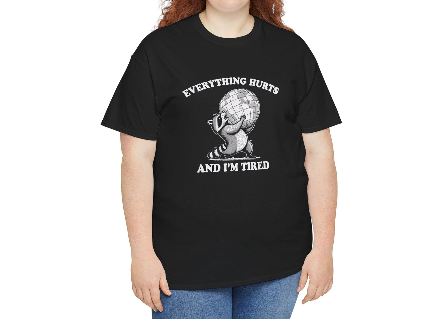 Modeled view of black T-shirt featuring a vintage style sketch of a raccoon carrying the world with the phrase “Everything Hurts and I’m Tired.” The official uniform of burnt out. Part of the Vivid Divergence Memewear Collection!