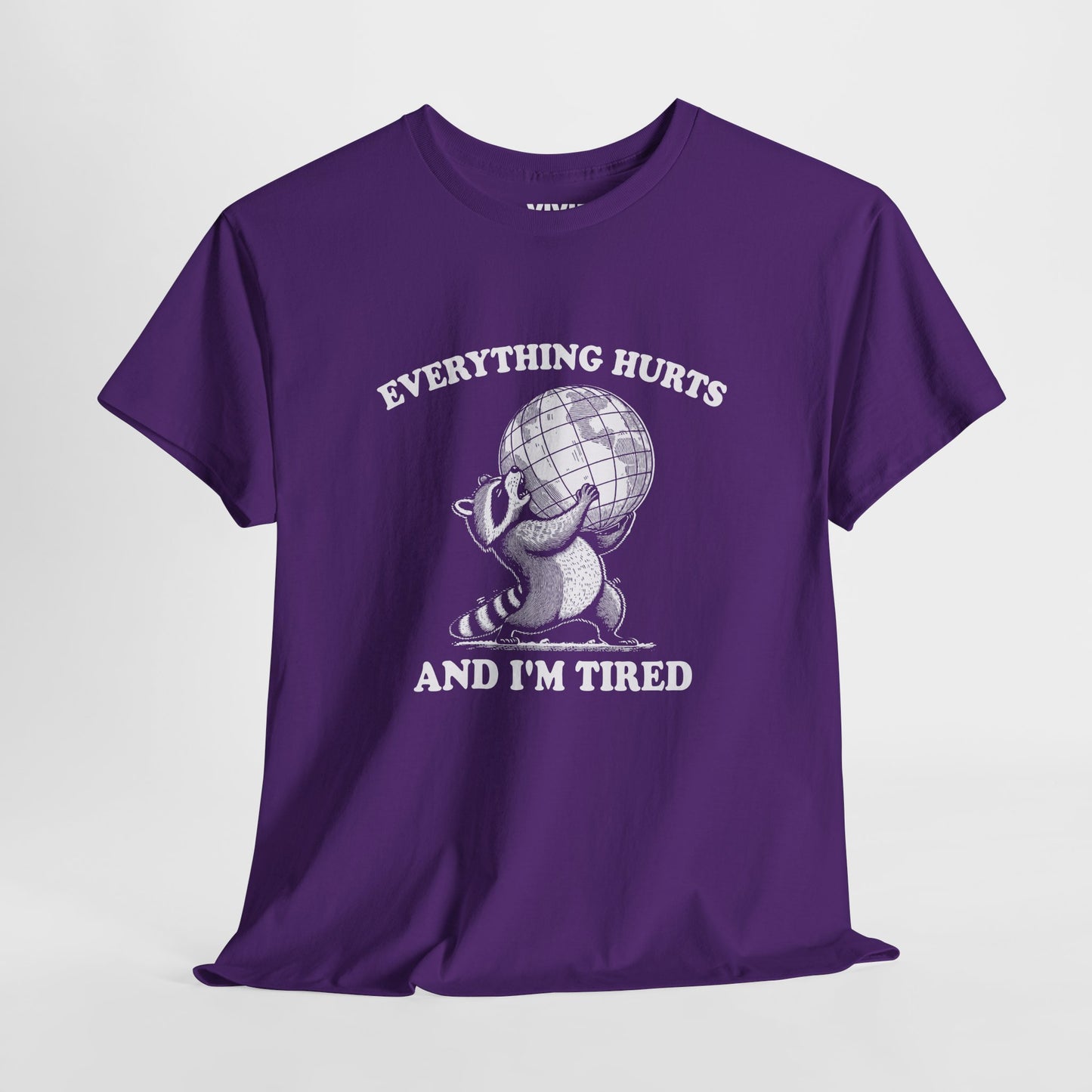 Hanging view of purple T-shirt featuring a vintage style sketch of a raccoon carrying the world with the phrase “Everything Hurts and I’m Tired.” The official uniform of burnt out. Part of the Vivid Divergence Memewear Collection!