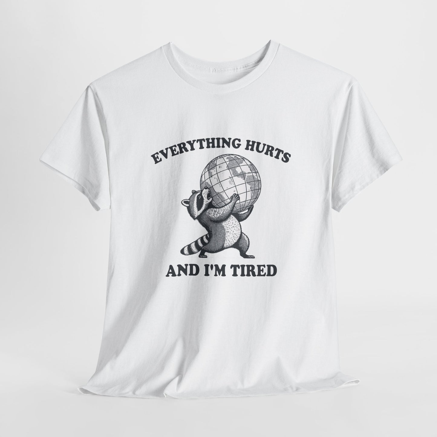 Hanging view of white T-shirt featuring a vintage style sketch of a raccoon carrying the world with the phrase “Everything Hurts and I’m Tired.” The official uniform of burnt out. Part of the Vivid Divergence Memewear Collection!