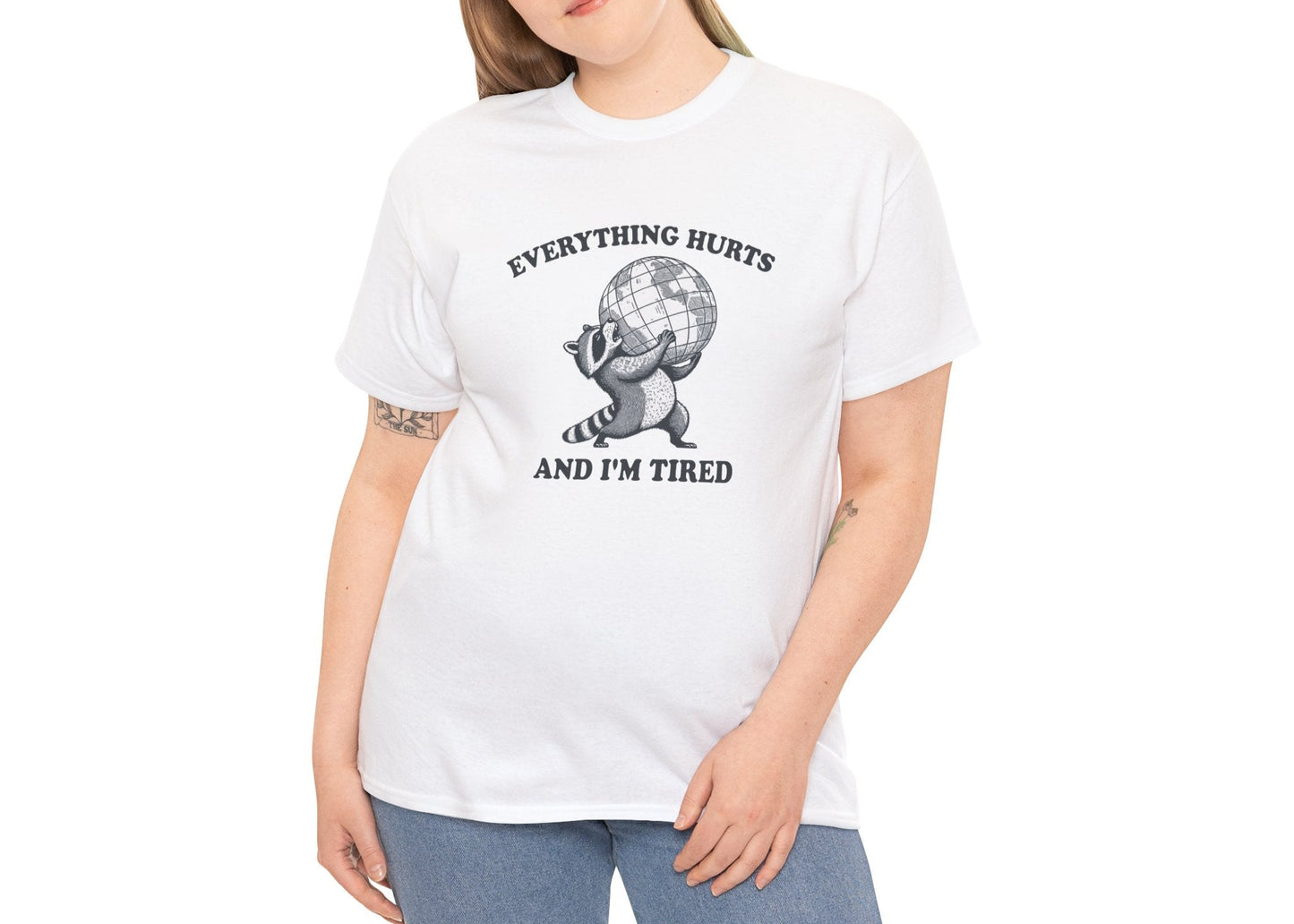 Modeled view of white T-shirt featuring a vintage style sketch of a raccoon carrying the world with the phrase “Everything Hurts and I’m Tired.” The official uniform of burnt out. Part of the Vivid Divergence Memewear Collection!
