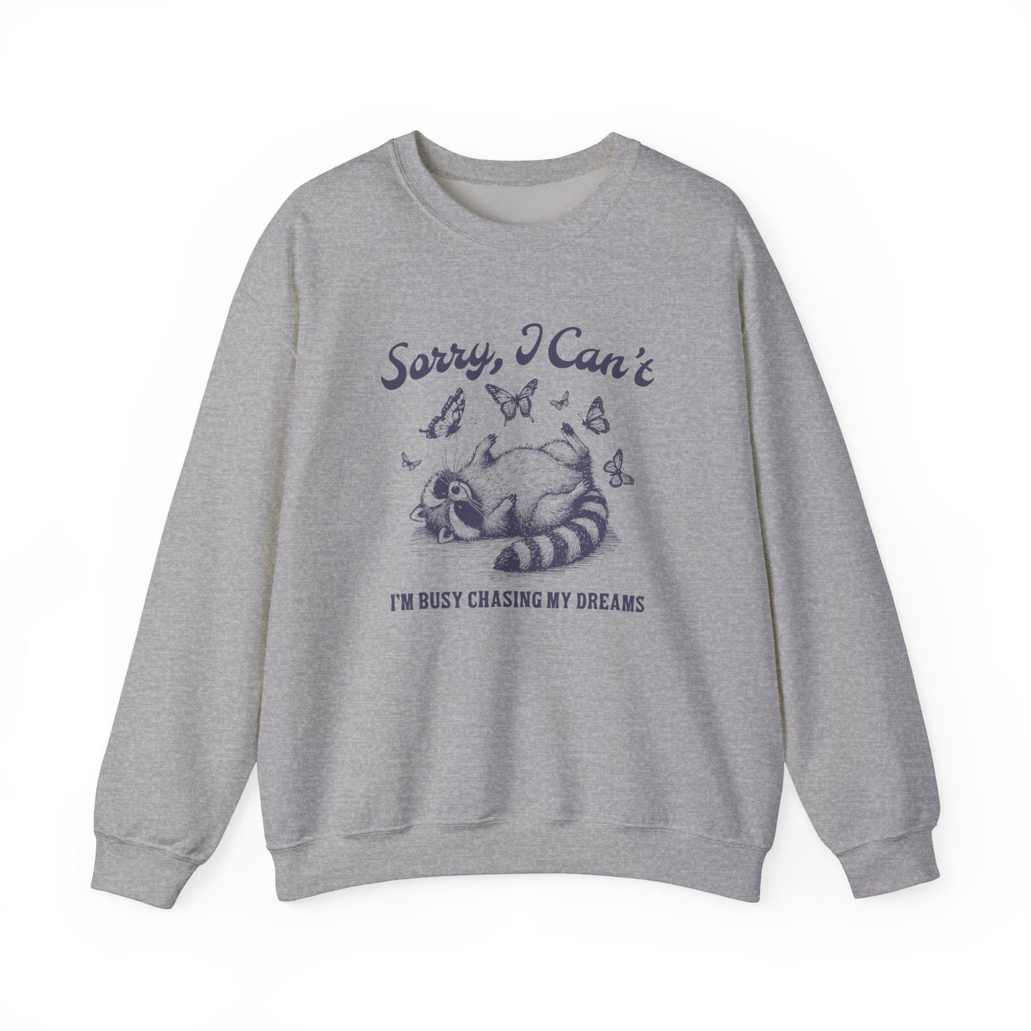 Front view of a gray sweater jumper with the text "Sorry, I Can't. I'm Busy Chasing My Dreams" and a cartoon raccoon illustration sleeping on a crescent moon. Part of the Vivid Divergence Sensory Friendly Unisex Sweater Jumper Range.