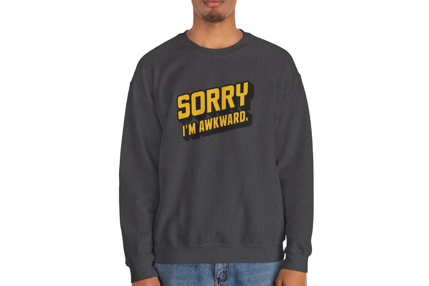 Model wearing a gray sweater jumper with the text "Sorry, I'm Awkward." in bold yellow lettering. Part of the Vivid Divergence Sensory Friendly Unisex Sweater Jumper Range.