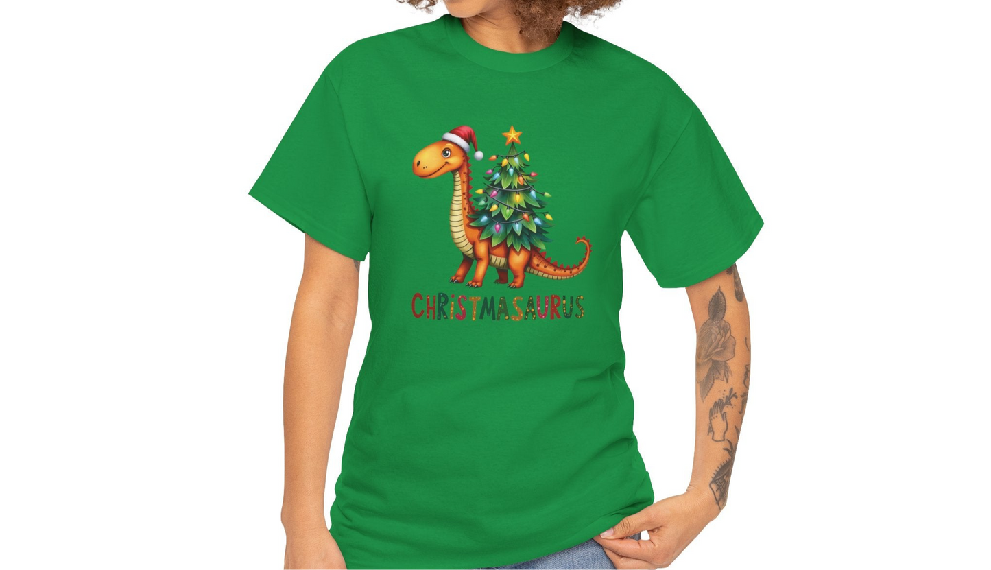 Model wearing a green T-shirt featuring a festive dinosaur decorated as a Christmas tree with ornaments and lights, styled casually for the holiday season. Part of the Vivid Divergence Sensory Friendly Unisex Tees Range.