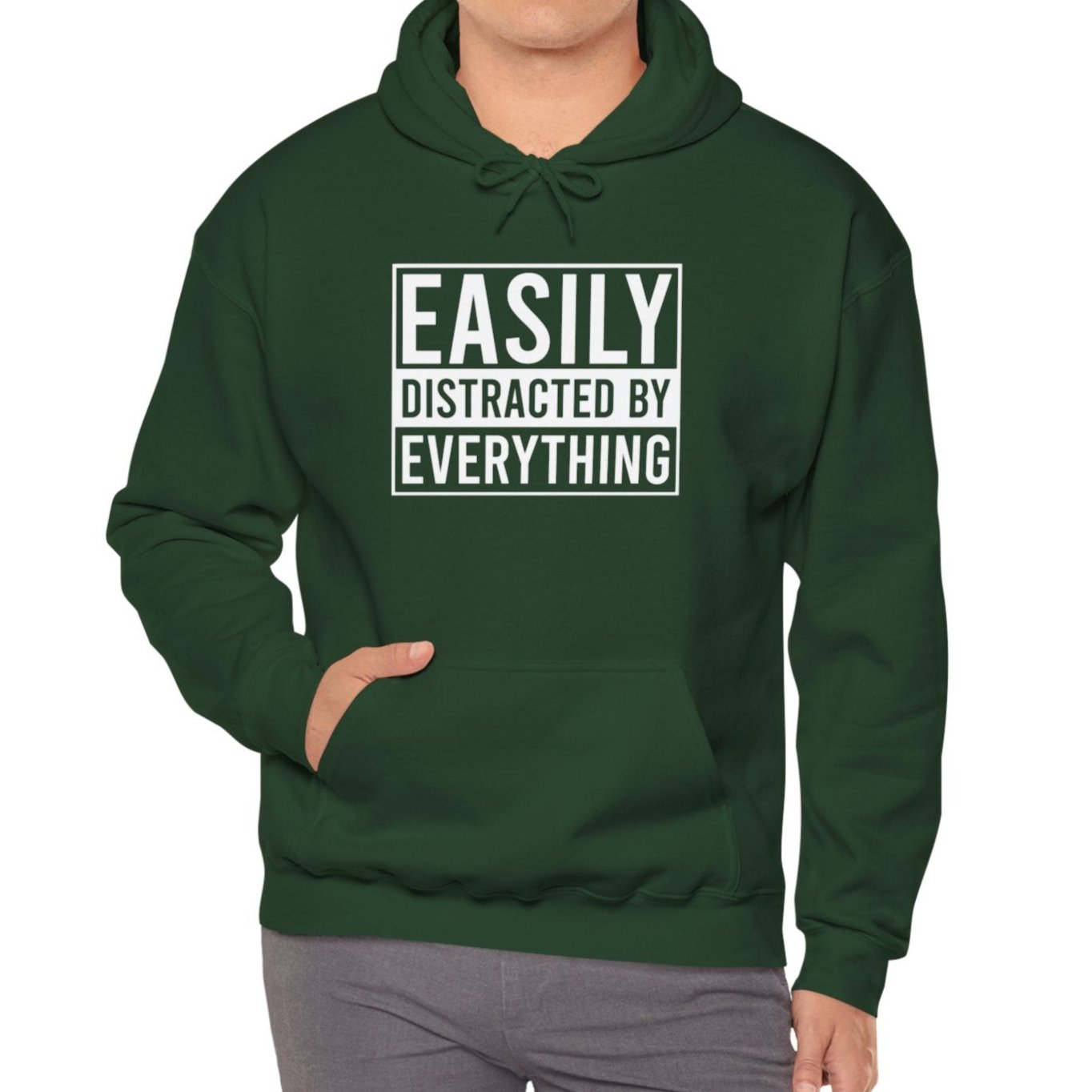 Model wearing a green hoodie with the text "Easily Distracted by Everything" in bold white lettering. Part of the Vivid Divergence Sensory Friendly Unisex Hoodie Range.