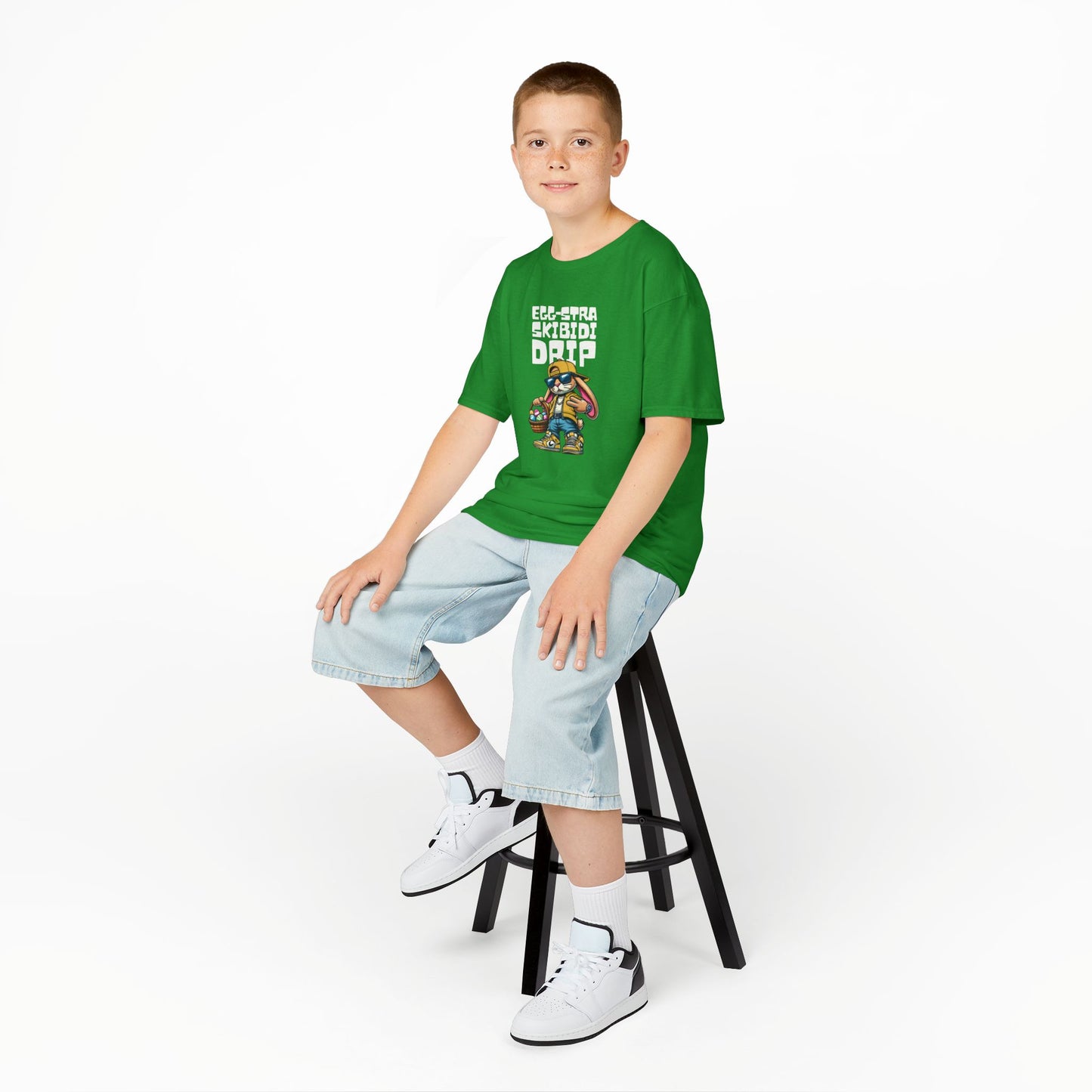 Child wearing a green Easter T-shirt with a stylish Skibidi bunny and "Egg-Stra Skibidi Drip" text, a cool holiday look. Hop into the season in style and shop Easter shirts online today!