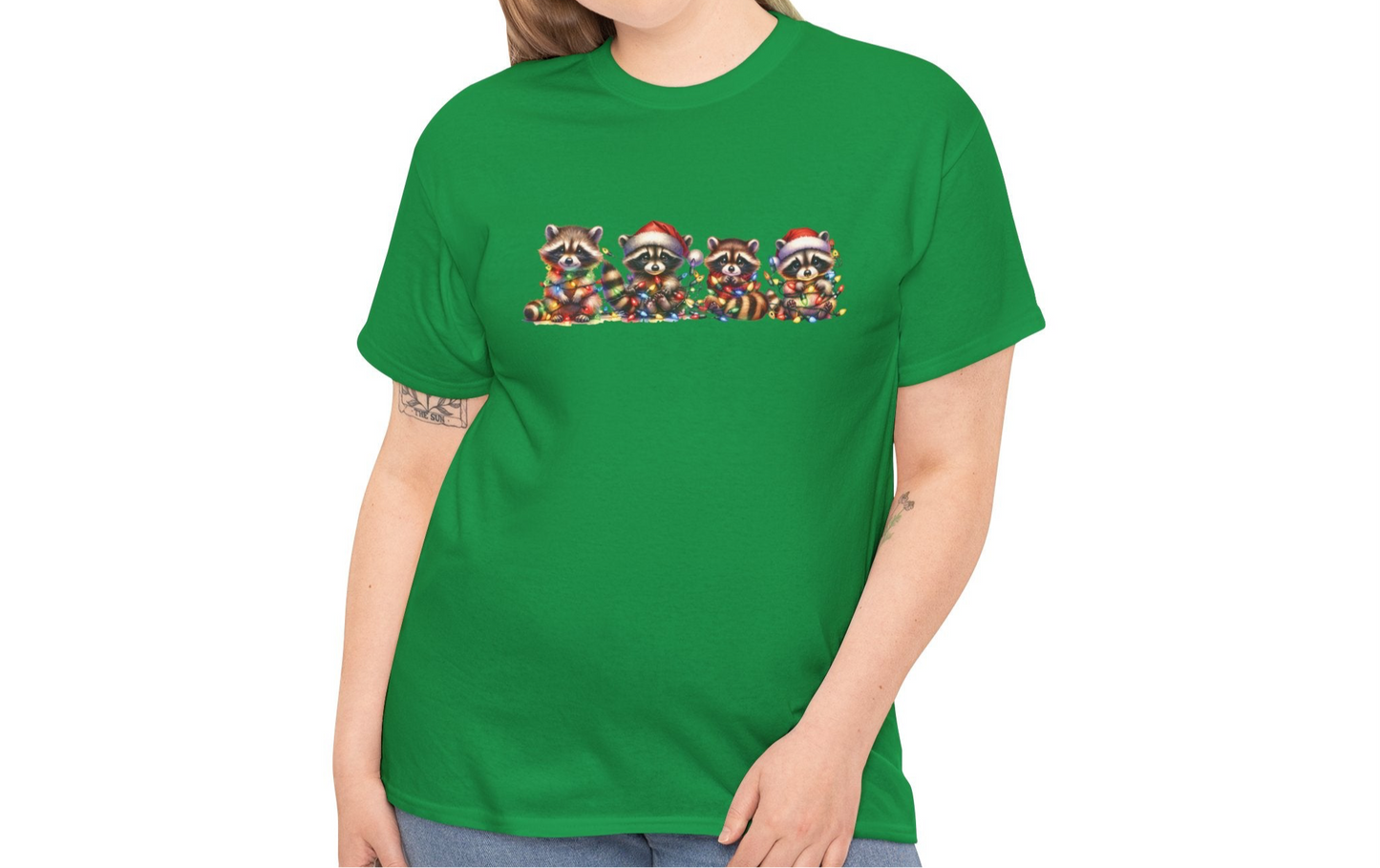 Model wearing a green T-shirt featuring a festive illustration of raccoons in Christmas attire causing holiday chaos, styled casually. Part of the Vivid Divergence Sensory Friendly Unisex Tees Range.