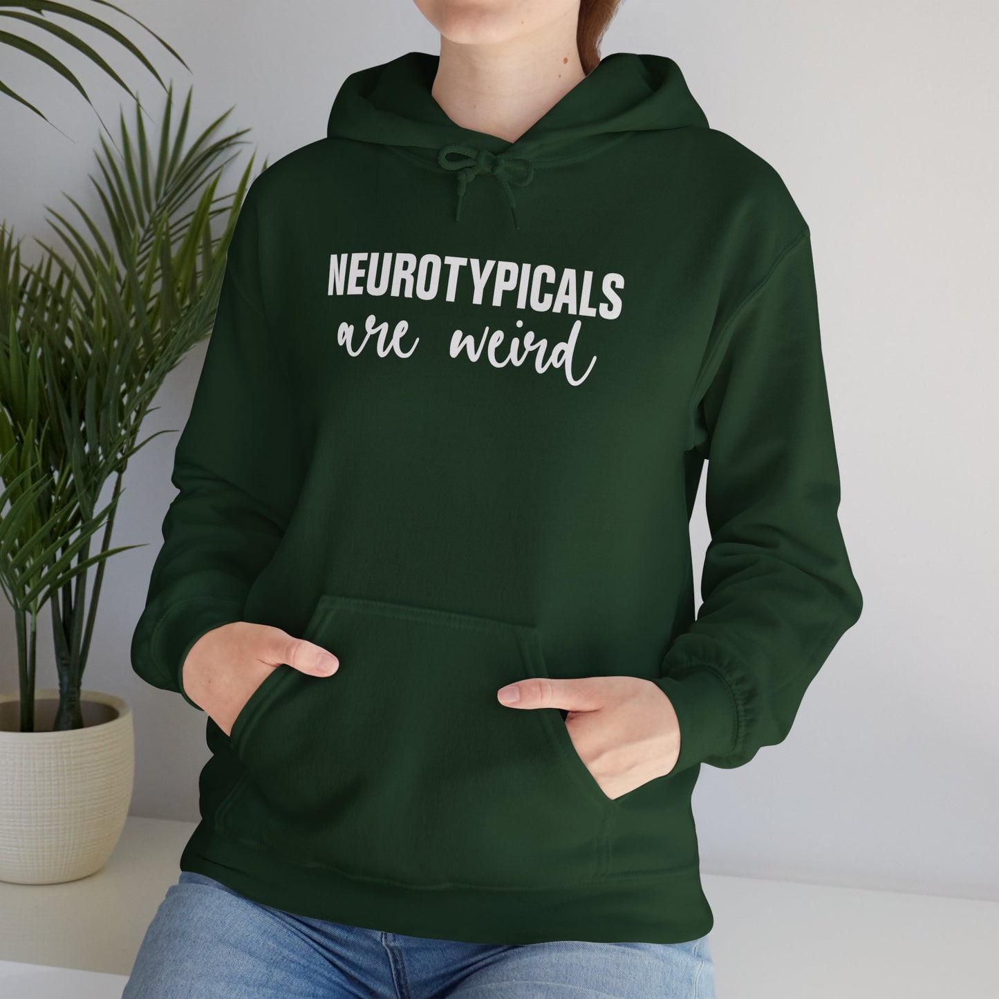 Model wearing a green hoodie featuring the text "Neurotypicals Are Weird" in bold white lettering. Part of the Vivid Divergence Sensory Friendly Unisex Hoodie Range.
Image Name:
