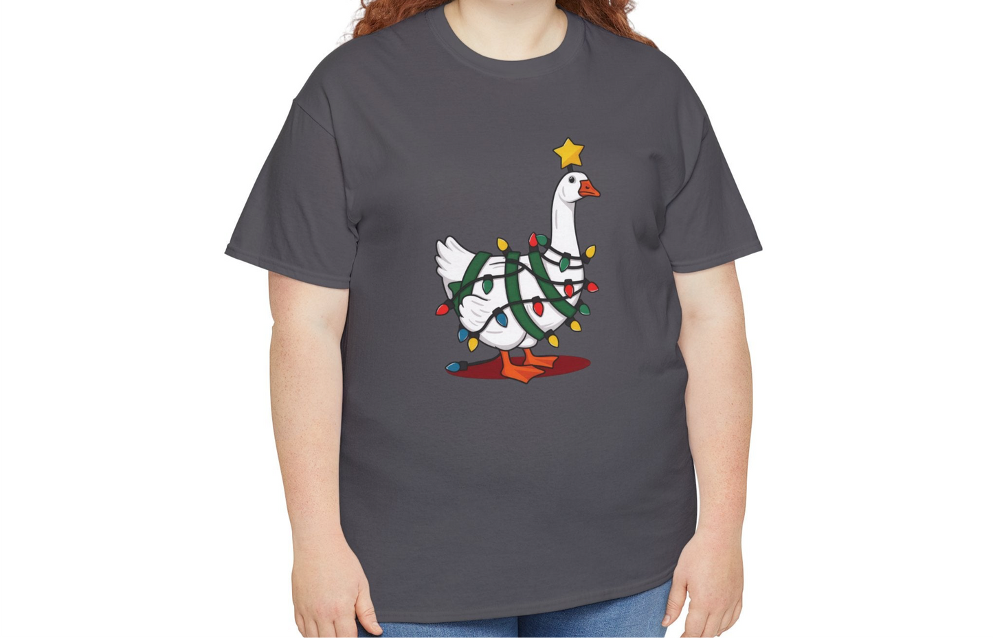 Model wearing a grey T-shirt featuring a festive illustration of a goose wearing a Santa hat and stringing Christmas lights, with the text "Goose on the Loose." Part of the Vivid Divergence Sensory Friendly Unisex Tees Range.