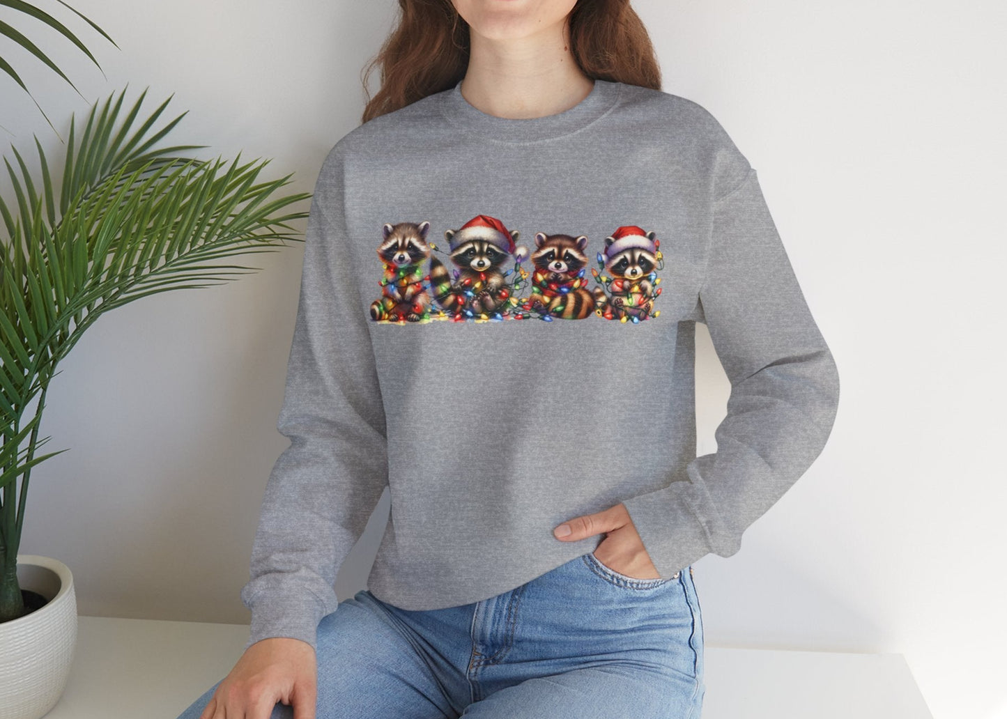 Model wearing a grey sweatshirt featuring a festive illustration of raccoons in Christmas attire causing holiday chaos. Part of the Vivid Divergence Sensory Friendly Unisex Sweater Jumper Range.
