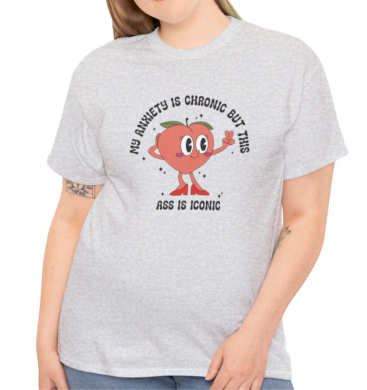 Close-up of a person wearing a grey T-shirt with the text "My Anxiety Is Chronic But This Ass Is Iconic" paired with a denim jacket. Part of the Vivid Divergence Sensory Friendly Unisex Tees Range.