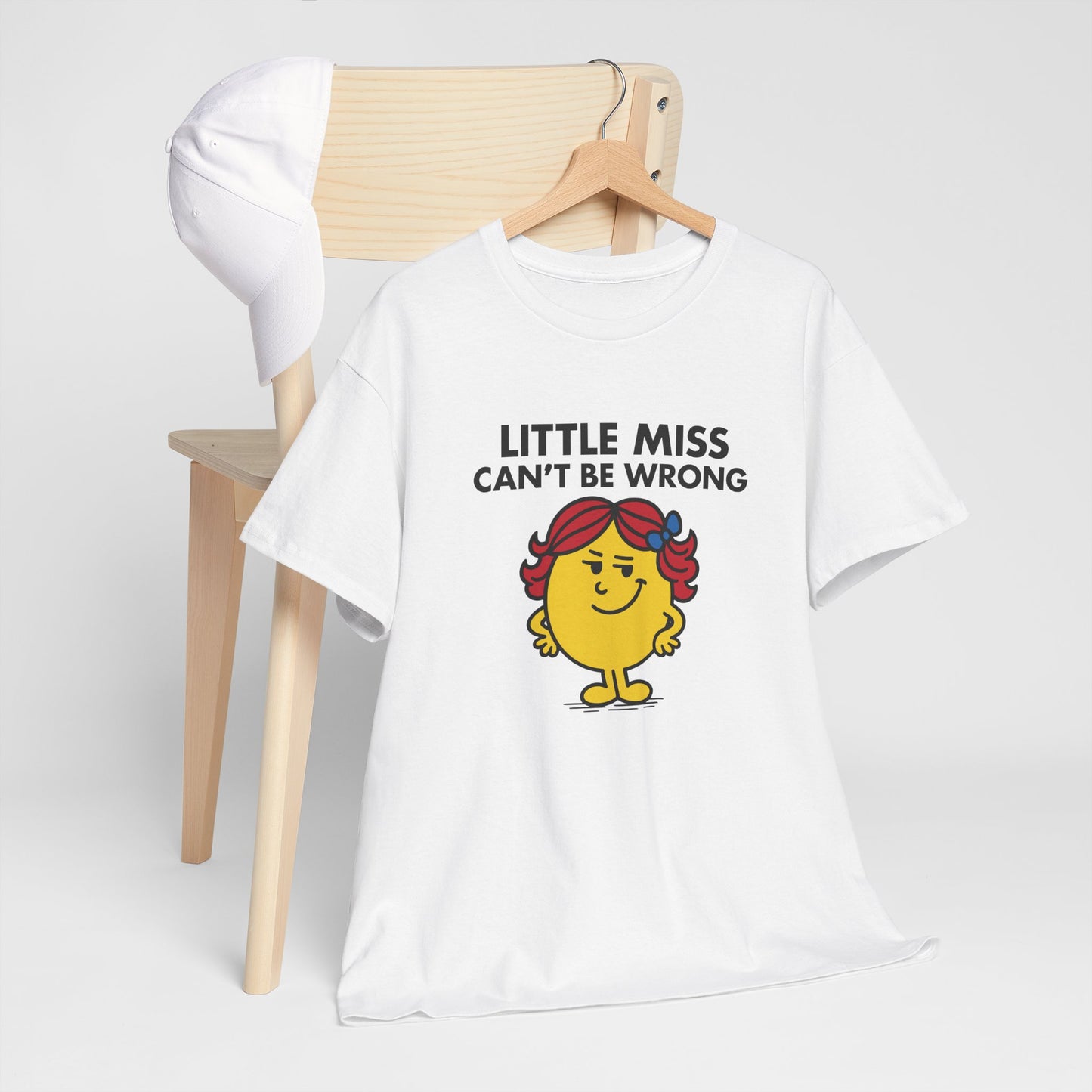 Little Miss Can’t Be Wrong T-shirt draped over a chair in a cozy setting. Part of the Little Miss Meme Character Collection. A Vivid Divergence Sensory Friendly Unisex Tee.