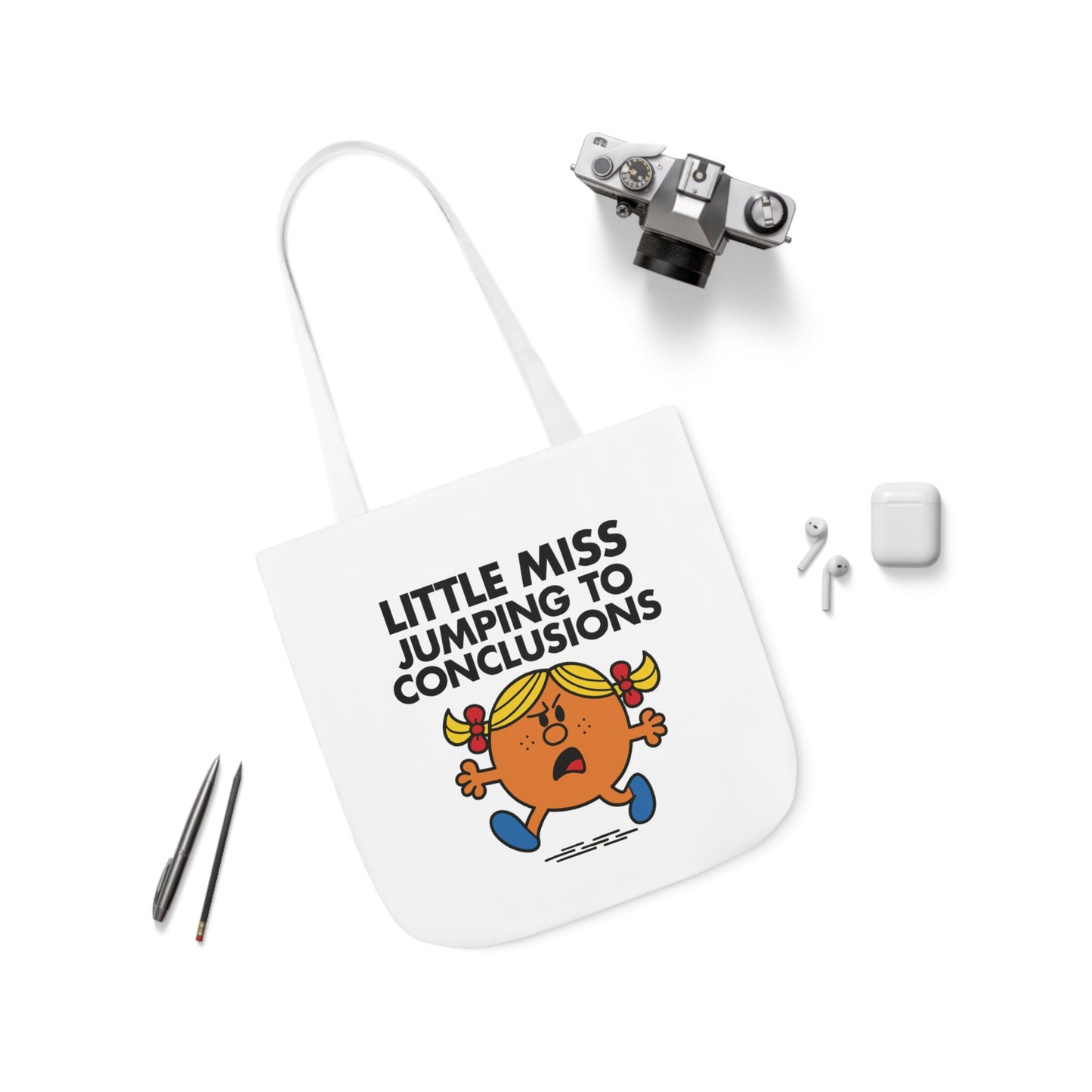Flat lay of tote bag with Little Miss Jumping To Conclusions surrounded by accessories. She reread the message 12 times — still spiraling. Part of the Vivid Divergence Little Miss Meme Collection!