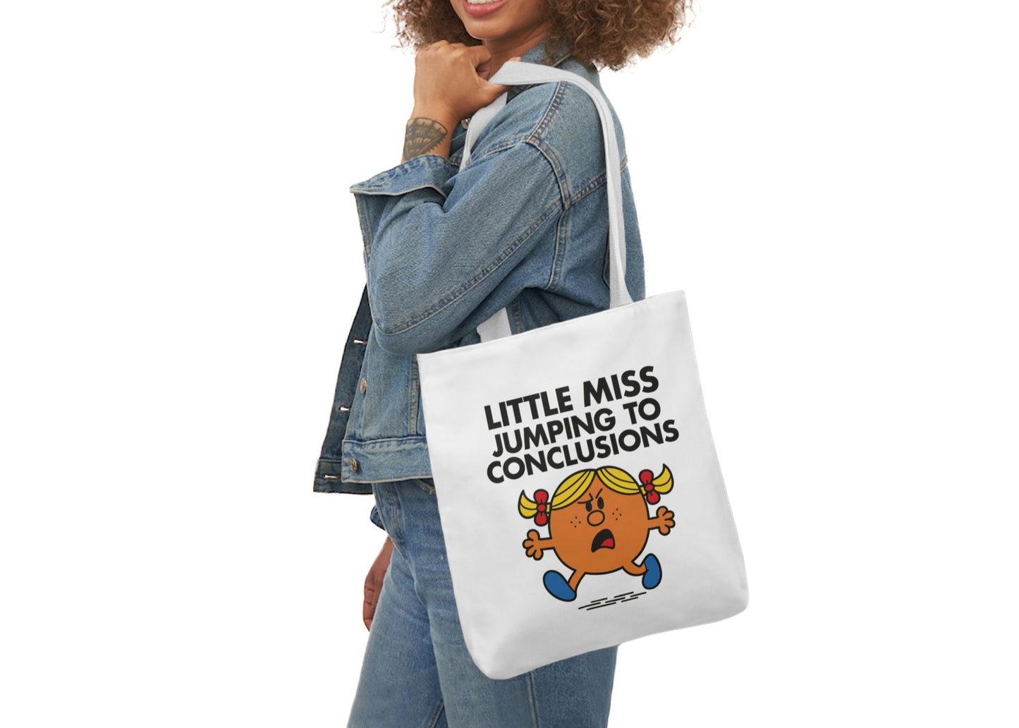 Woman in denim modeling the Little Miss Jumping To Conclusions tote bag over her shoulder. She’s bracing for a plot twist that isn’t coming. Part of the Vivid Divergence Little Miss Meme Collection!