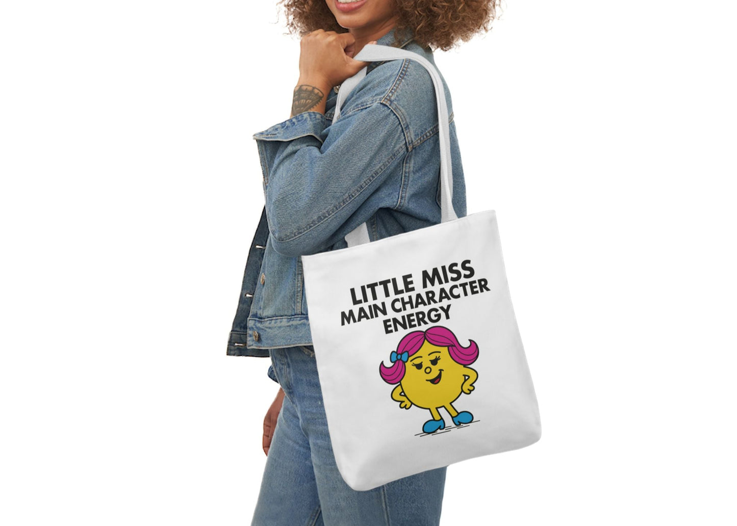Woman wearing denim jacket carrying tote bag with "Little Miss Main Character Energy" design. Part of the Vivid Divergence Little Miss Meme Collection!