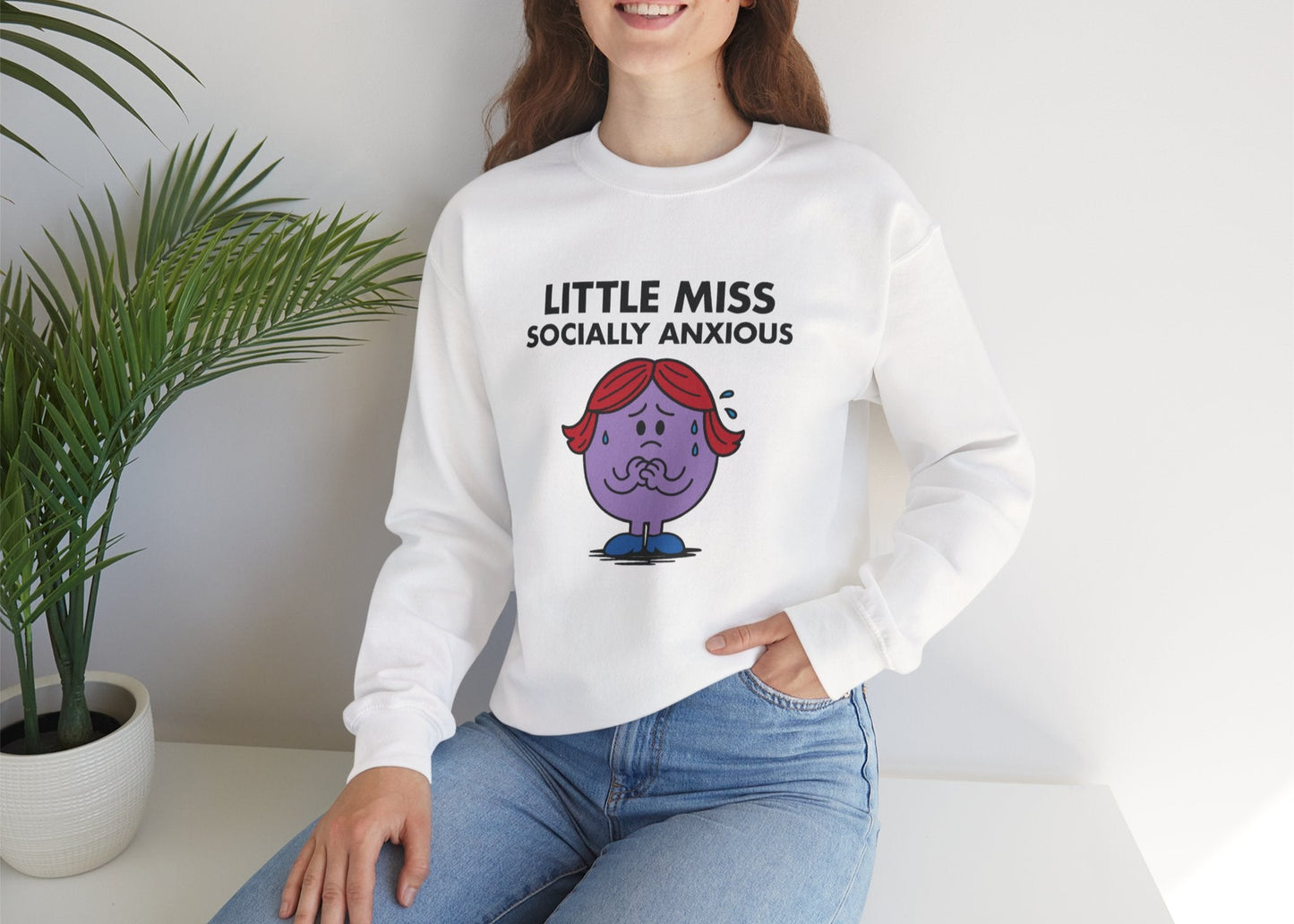 Person wearing the Little Miss Socially Anxious sweatshirt while seated casually. Part of the Little Miss Meme Character Collection. A Vivid Divergence Sensory Friendly Sweater Jumper.