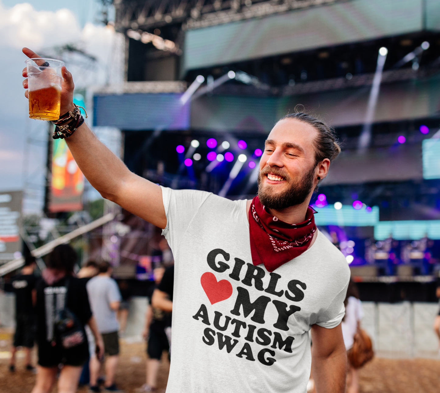 A man at an event wearing a white T-shirt with the text "Girls Love My Autism Swag" featuring a red heart design. Part of the Vivid Divergence Sensory Friendly Unisex Tees Range.