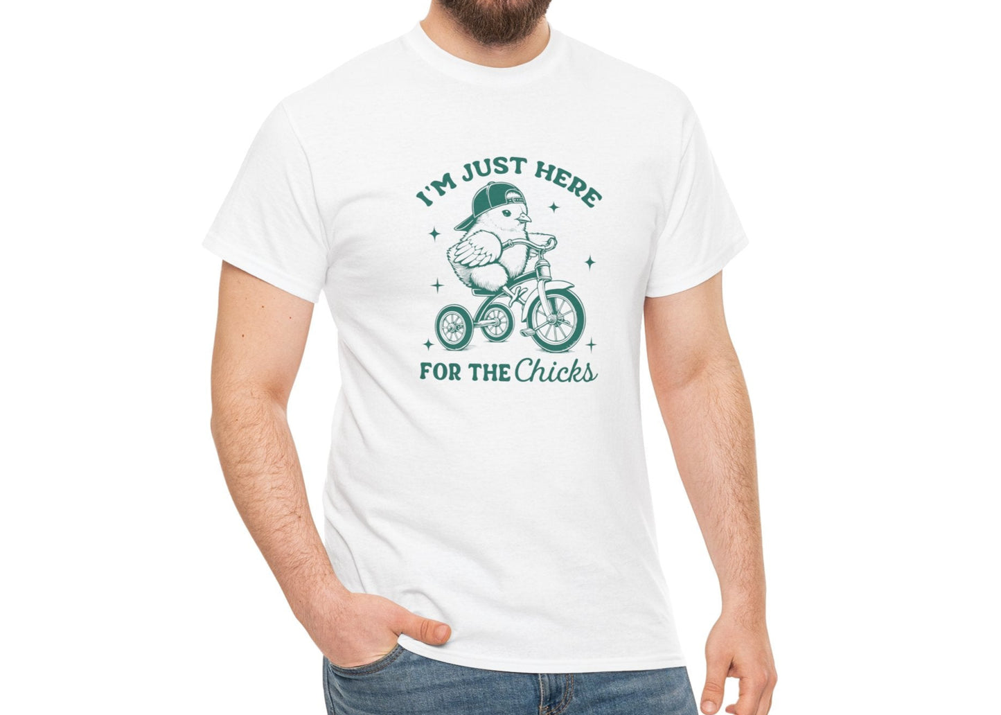 Man wearing a white Easter T-shirt featuring "I'm Just Here for the Chicks" text with a chick riding a bicycle, a humorous and fun holiday look. Hop into the season in style and shop Easter shirts online today!