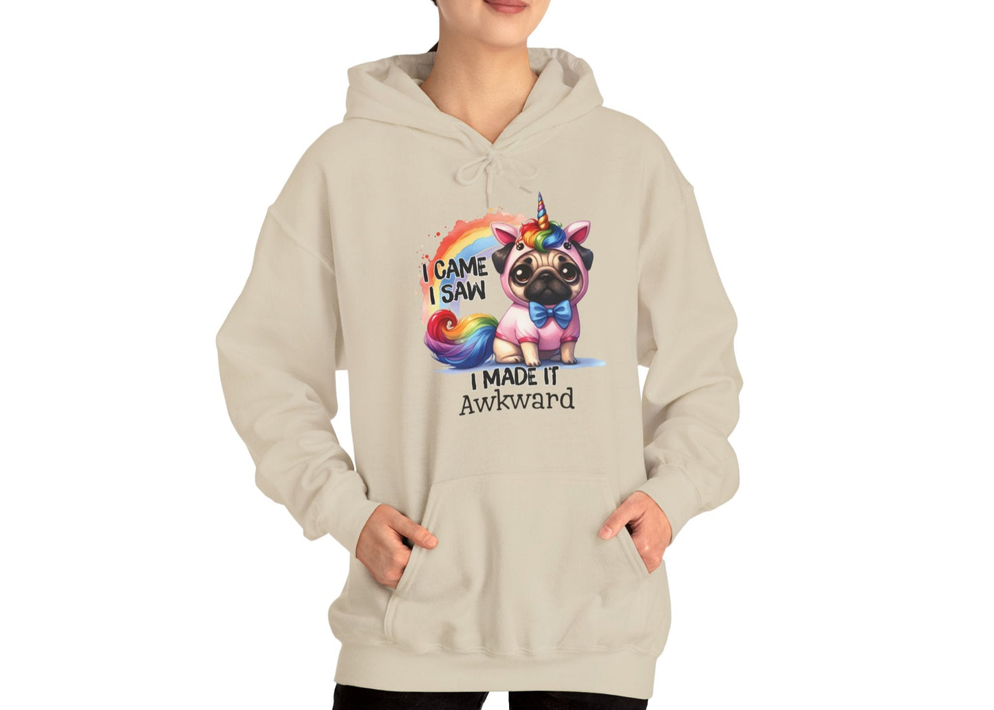 Model wearing a beige hoodie with a colorful unicorn pug and the text "I Came, I Saw, I Made It Awkward," standing with hands at sides. Part of the Vivid Divergence Sensory Friendly Unisex Hoodie Range.