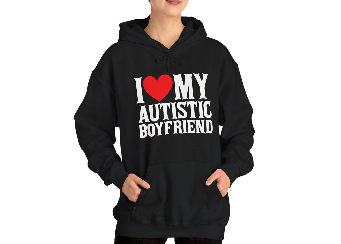Model wearing a black hoodie with bold white text that reads "I ❤️ My Autistic Boyfriend," standing with hands in pockets. Part of the Vivid Divergence Sensory Friendly Unisex Hoodie Range.