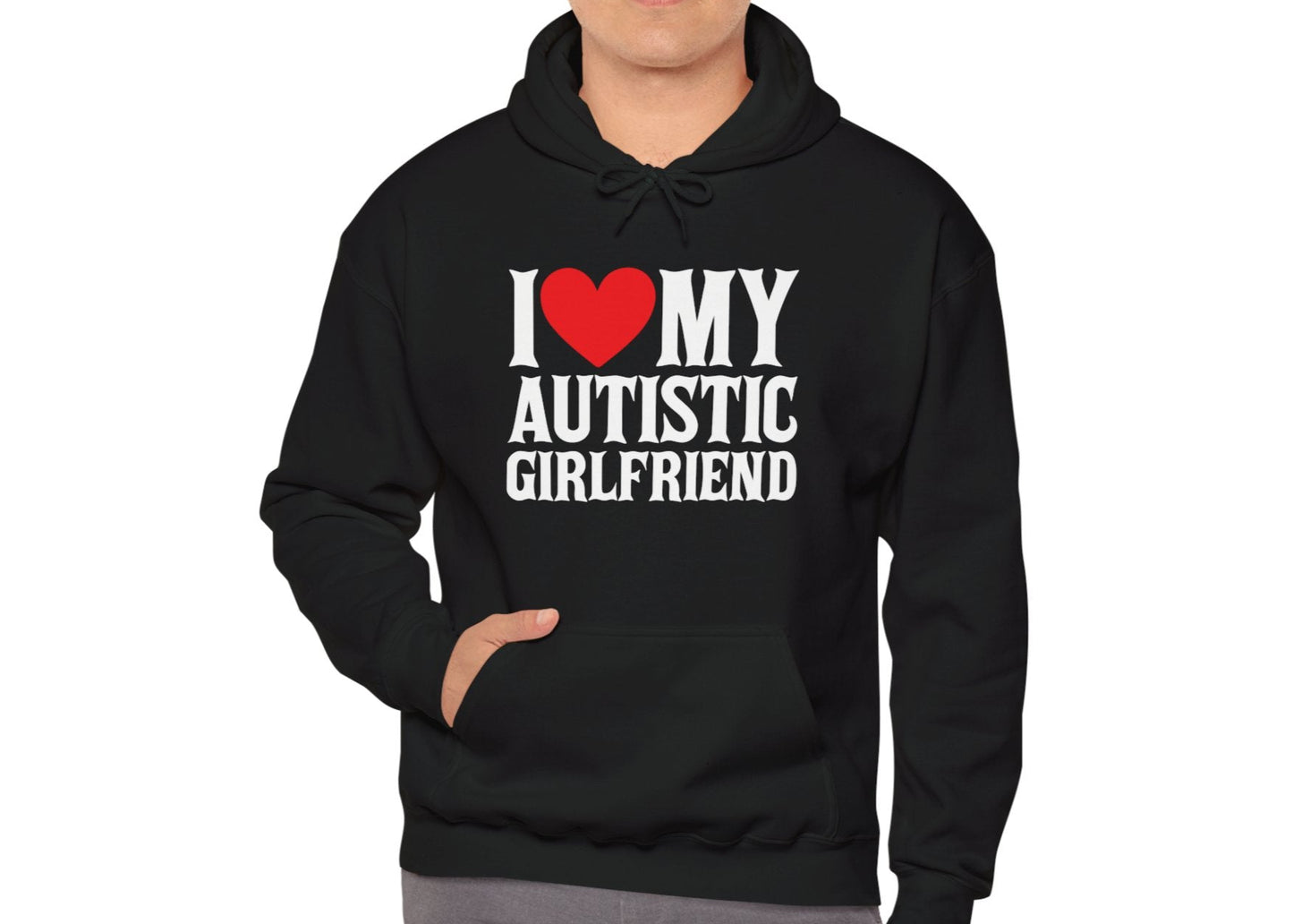 Model wearing a black hoodie with bold white text that reads "I ❤️ My Autistic Girlfriend," standing with hands in pockets. Part of the Vivid Divergence Sensory Friendly Unisex Hoodie Range.