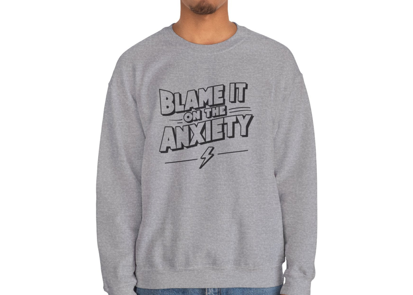 Model wearing a gray sweatshirt with bold text that reads "Blame It on the Anxiety," standing with hands at sides. Part of the Vivid Divergence Sensory Friendly Unisex Sweater Jumper Range.