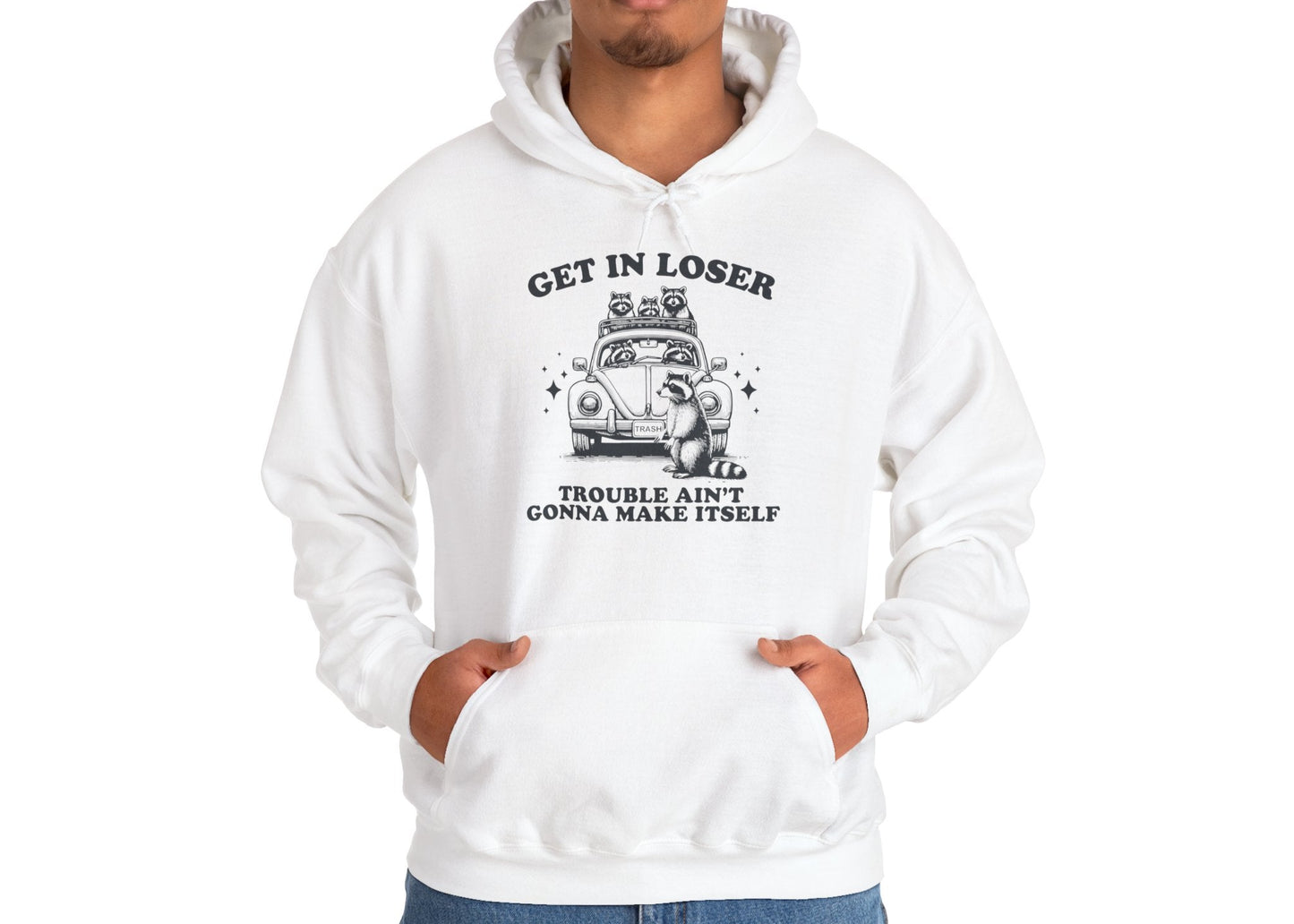 Model wearing a white hoodie with "Get in Loser, Trouble Ain't Gonna Make Itself" in black letters and a group of raccoons riding in a car, standing with hands in pockets. Part of the Vivid Divergence Sensory Friendly Unisex Hoodie Range.