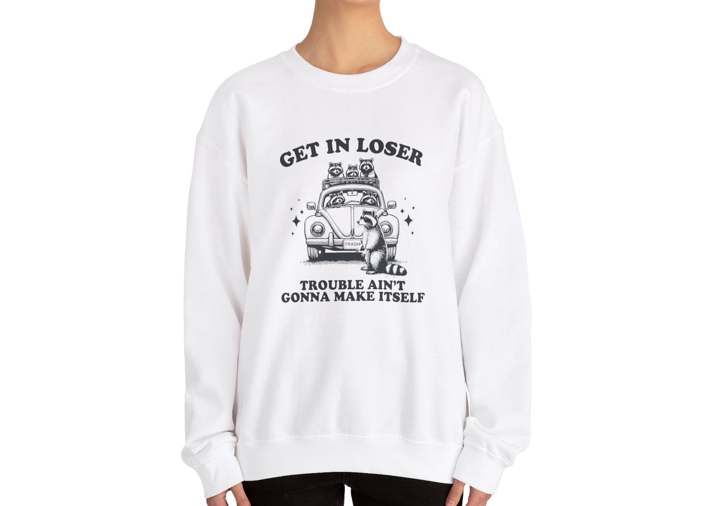 Model wearing a white sweatshirt with "Get in Loser, Trouble Ain't Gonna Cause Itself" in black letters and a group of raccoons in a car, standing with hands at sides. Part of the Vivid Divergence Sensory Friendly Unisex Sweater Jumper Range.