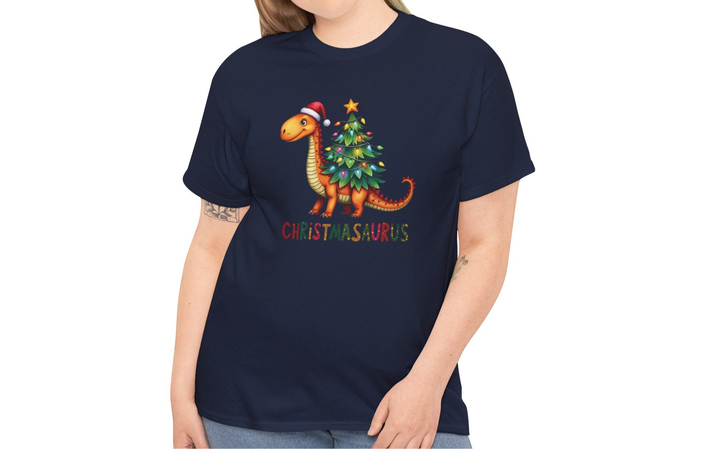 Model wearing a navy blue T-shirt featuring a festive dinosaur decorated as a Christmas tree with ornaments and lights, styled casually with jeans. Part of the Vivid Divergence Sensory Friendly Unisex Tees Range.