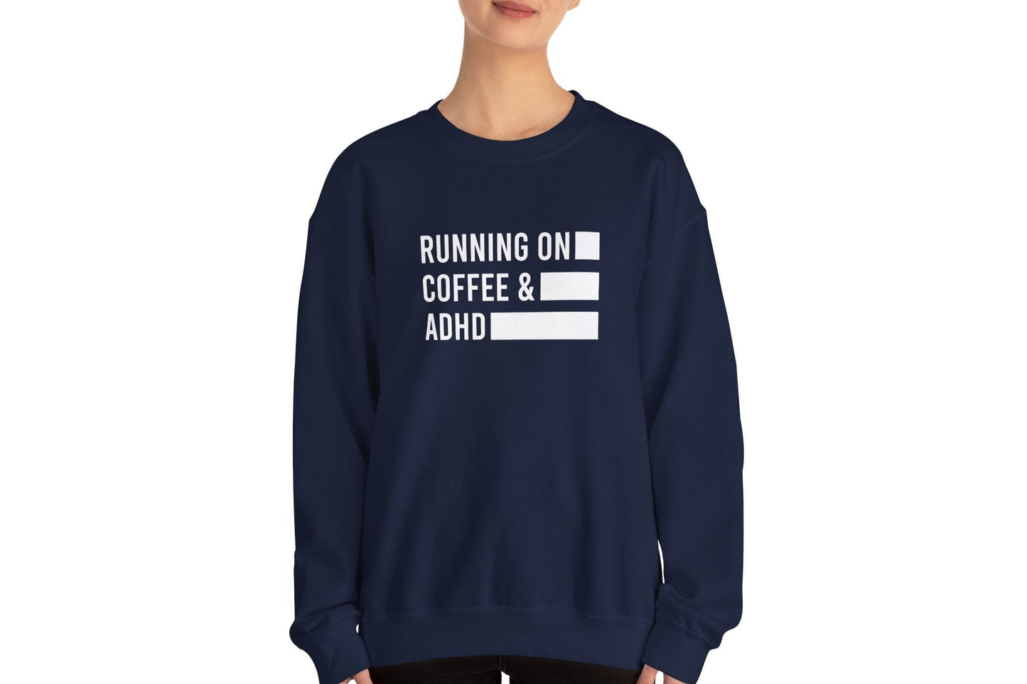 Model wearing a navy blue sweater jumper with the text "Running on Coffee & ADHD" in bold white lettering and a battery graphic. Part of the Vivid Divergence Sensory Friendly Unisex Sweater Jumper Range.