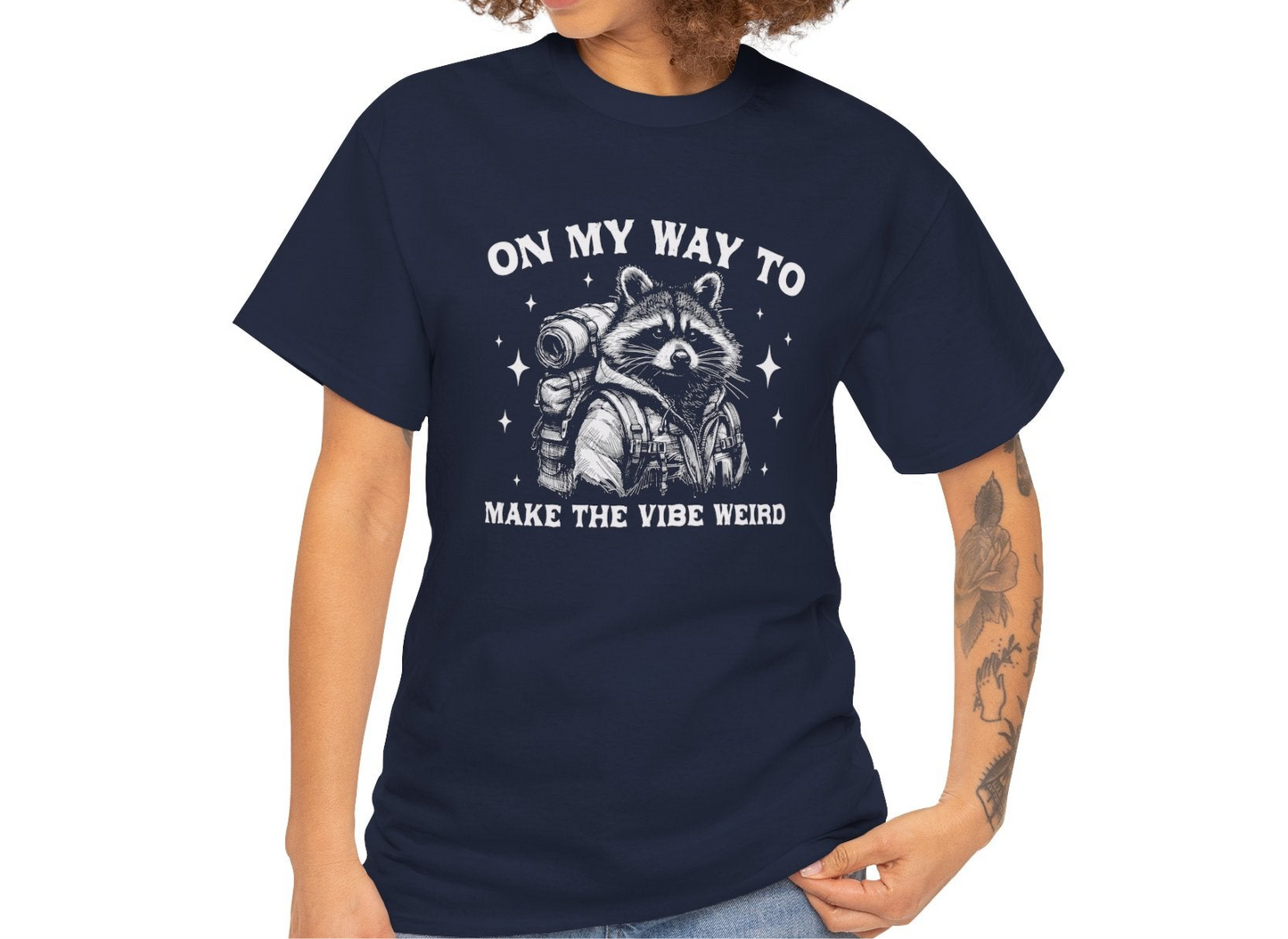Model wearing a navy T-shirt with "On My Way to Make the Vibe Weird" and a raccoon graphic in white text. Part of the Vivid Divergence Sensory Friendly Unisex Tees Range.