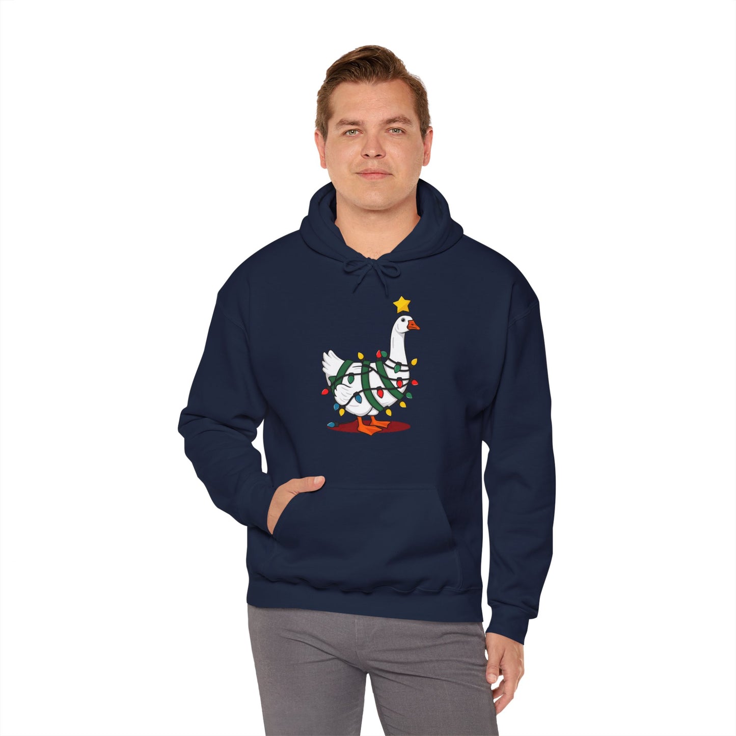 Model wearing a navy blue hoodie featuring a festive illustration of a goose wearing a Santa hat and stringing Christmas lights, with the text "Goose on the Loose." Part of the Vivid Divergence Sensory Friendly Unisex Hoodie Range.
