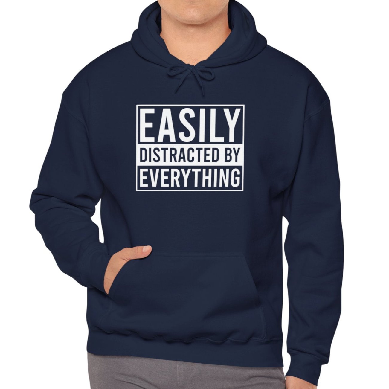 Model wearing a navy blue hoodie with the text "Easily Distracted by Everything" in bold white lettering. Part of the Vivid Divergence Sensory Friendly Unisex Hoodie Range.