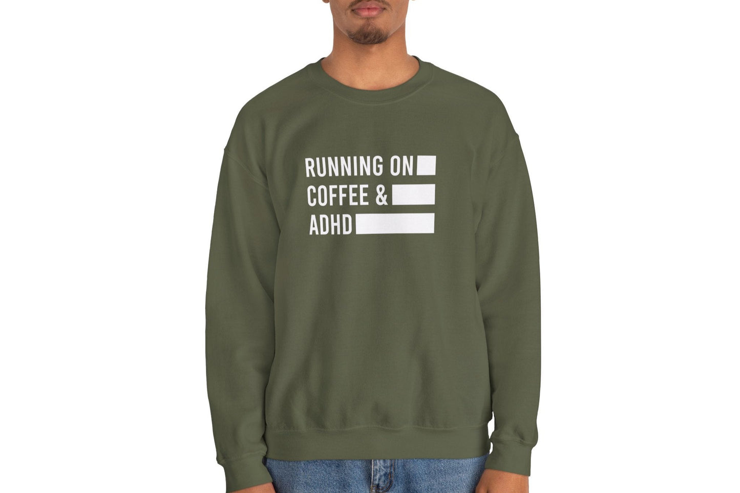 Model wearing an olive green sweater jumper with the text "Running on Coffee & ADHD" in bold white lettering and a battery graphic. Part of the Vivid Divergence Sensory Friendly Unisex Sweater Jumper Range.