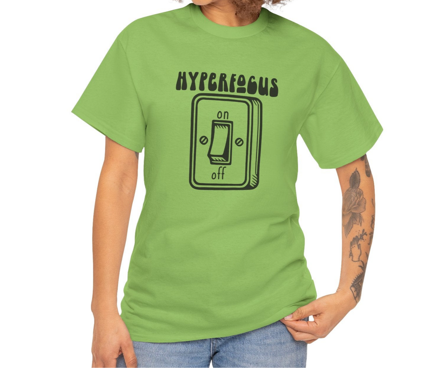 A person wearing a green T-shirt with the text "Hyperfocus" and an on/off switch graphic design. Part of the Vivid Divergence Sensory Friendly Unisex Tees Range.