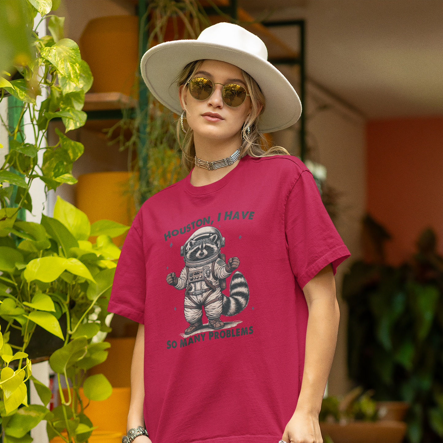 A person wearing a red T-shirt with an astronaut raccoon graphic and the text "Houston, I Have So Many Problems." Part of the Vivid Divergence Sensory Friendly Unisex Tees Range.