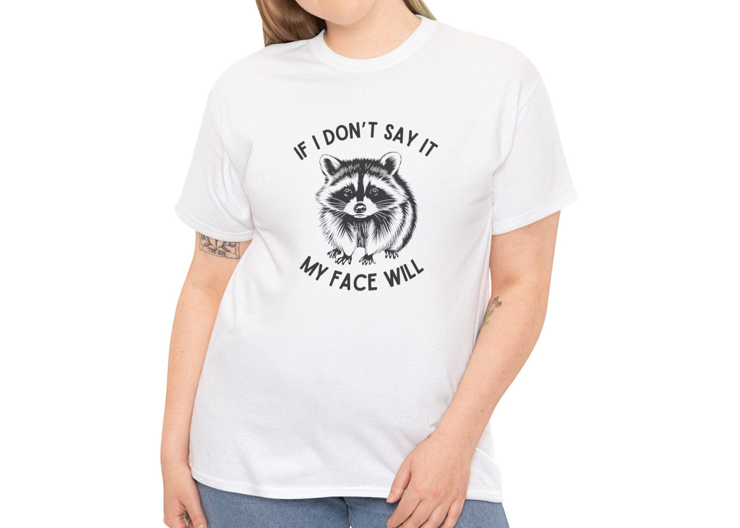 A person wearing a white T-shirt with a raccoon face graphic and the text "If I Don't Say It, My Face Will." Part of the Vivid Divergence Sensory Friendly Unisex Tees Range.