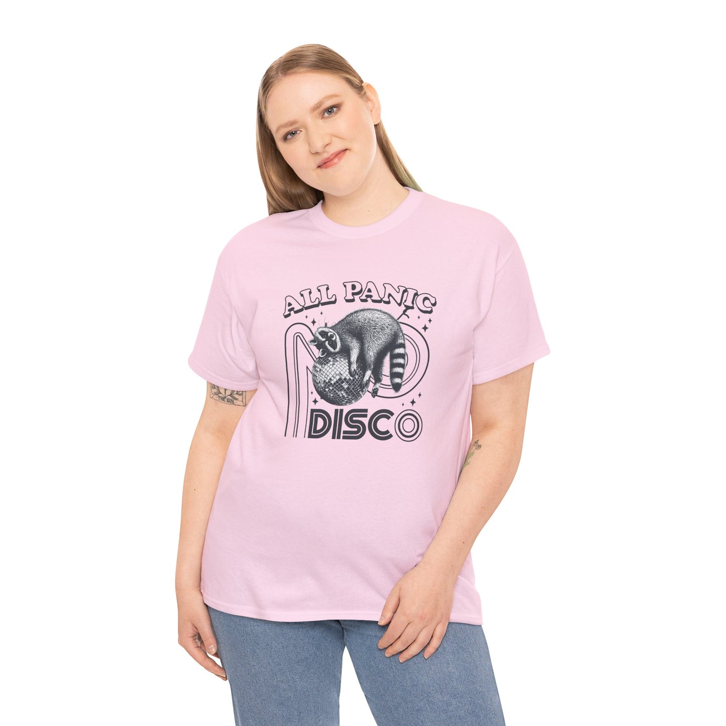 Model wearing a pink T-shirt featuring "All Panic No Disco" text with a raccoon illustration inside a disco ball. Part of the Vivid Divergence Sensory Friendly Unisex Tees Range.