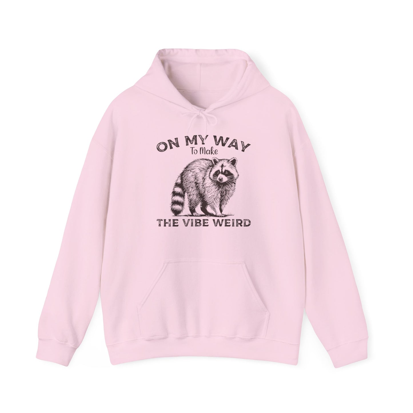 Front view of a pink hoodie featuring the text "On My Way to Make the Vibe Weird" and a cartoon illustration of a raccoon holding a stick. Part of the Vivid Divergence Sensory Friendly Unisex Hoodie Range.
