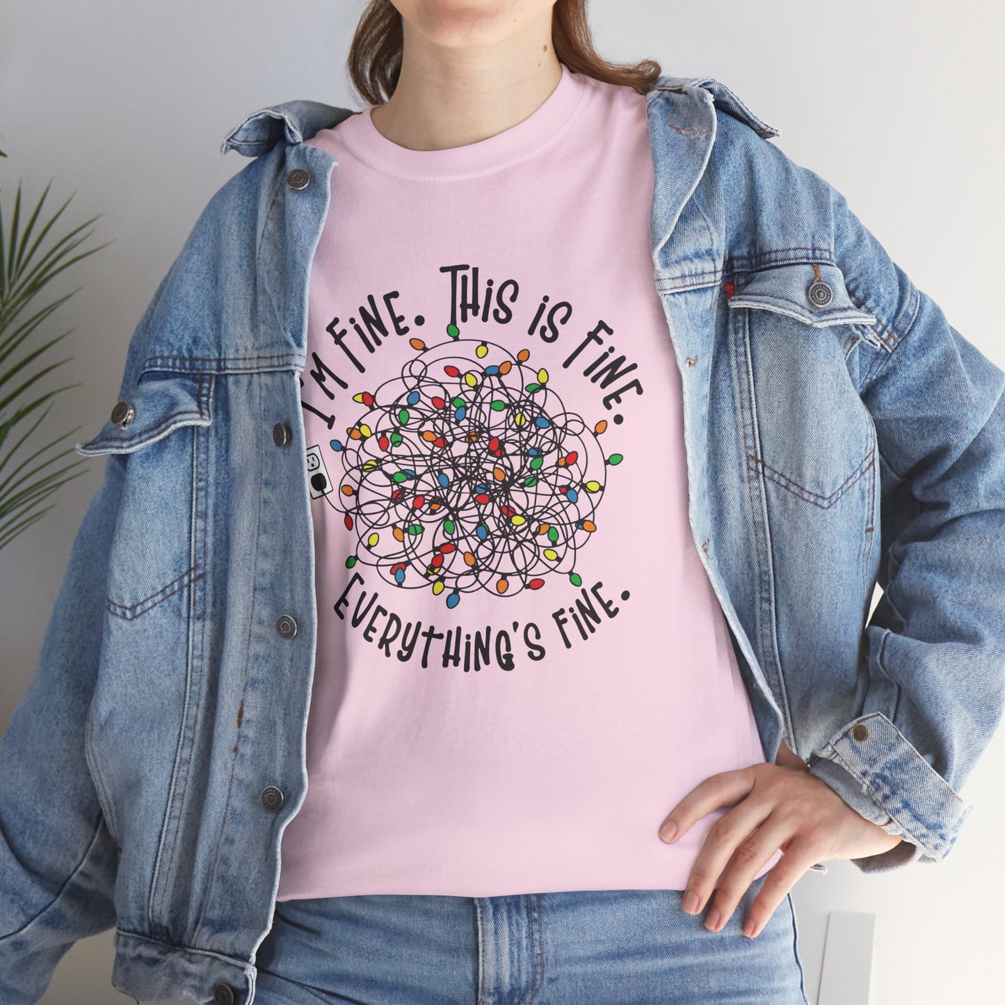 Model wearing a pink T-shirt with a festive tangled Christmas lights design, paired with a denim jacket. Part of the Vivid Divergence Sensory Friendly Unisex Tees Range.