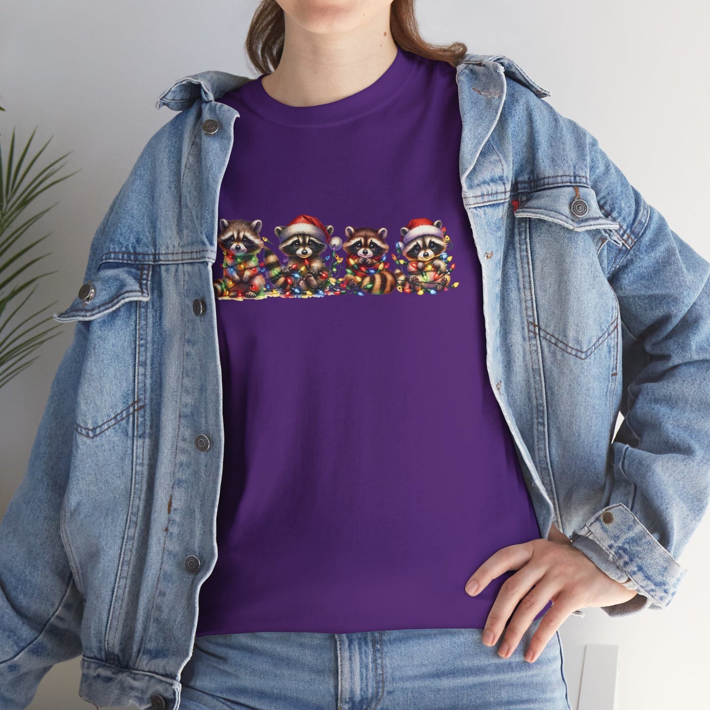 Model wearing a purple T-shirt featuring a festive illustration of raccoons in Christmas attire causing holiday chaos, styled casually. Part of the Vivid Divergence Sensory Friendly Unisex Tees Range.
